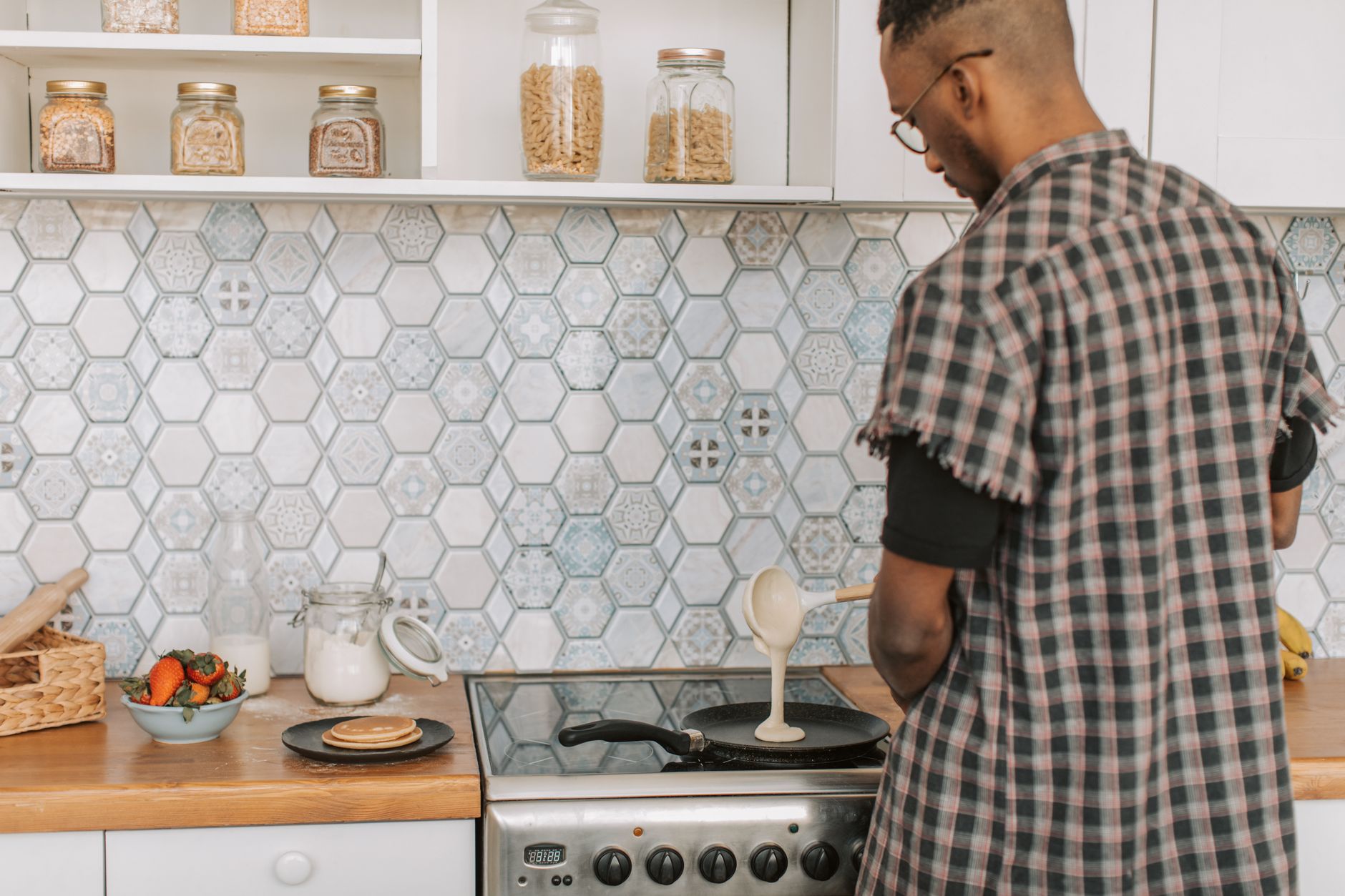 A man cooking at a stove in a tiled kitchen