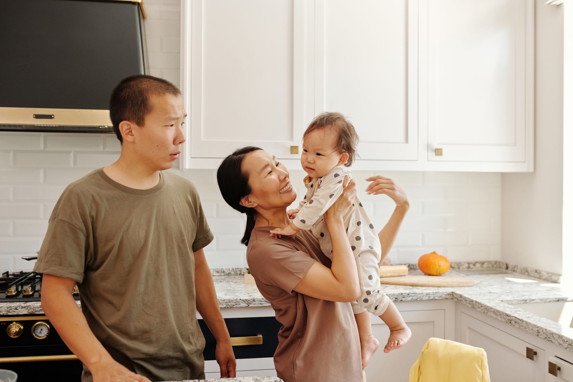 Parents holding a baby in a kitchen
