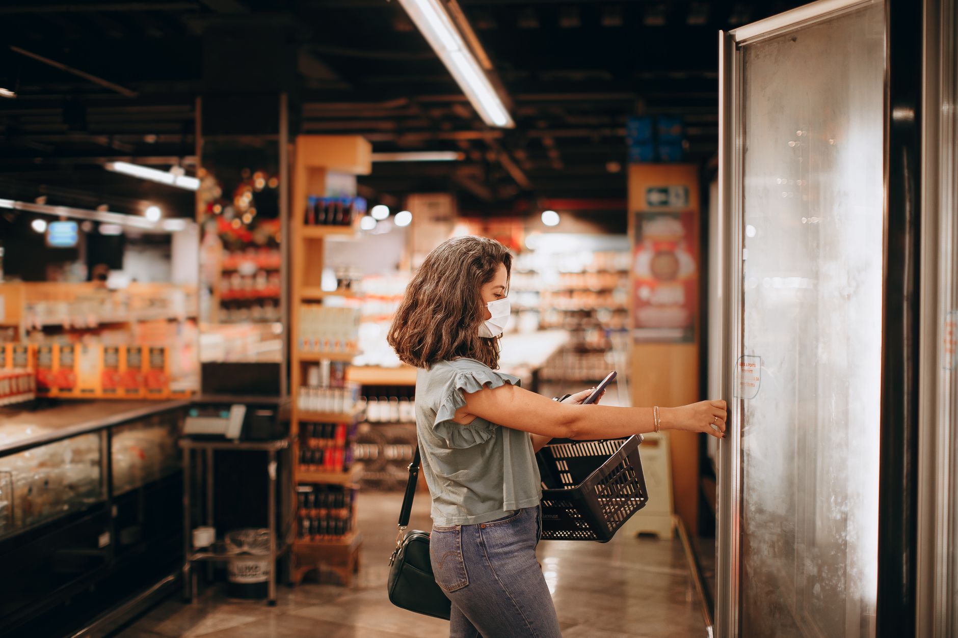 A shopper at a store freezer door