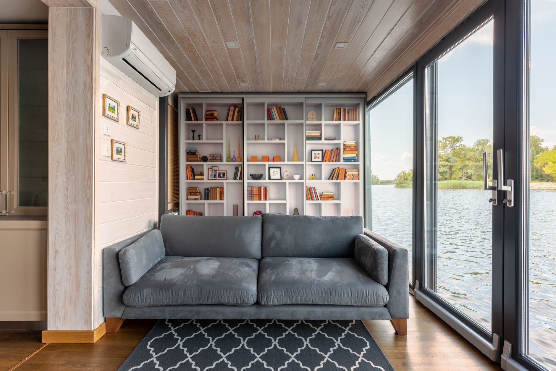 A tall bookcase behind a sofa in a lakeside living room
