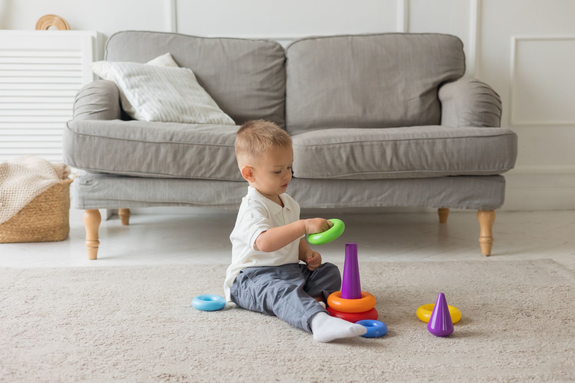 A toddler playing with stacking rings on a rug