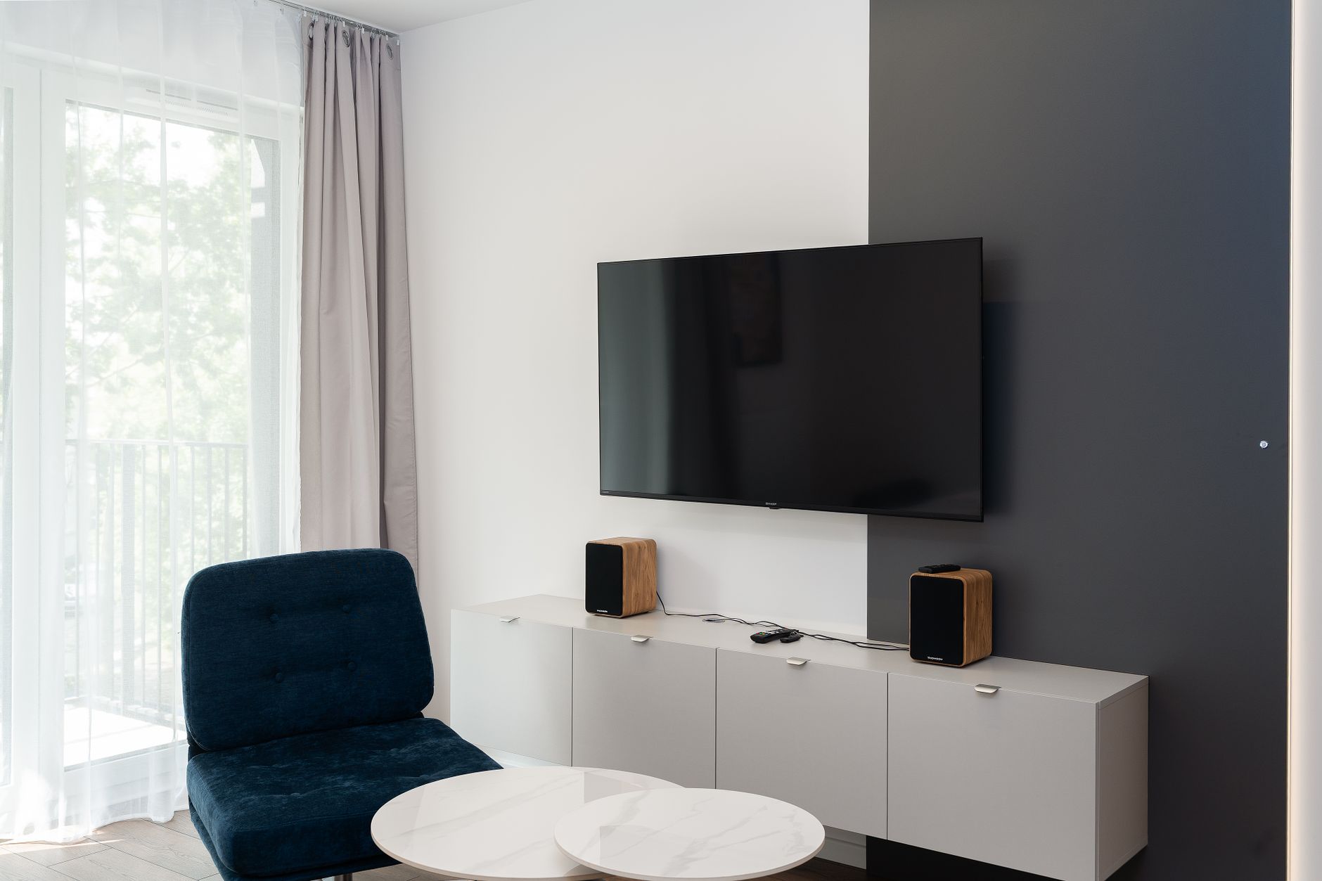 A wall-mounted TV above a low media console