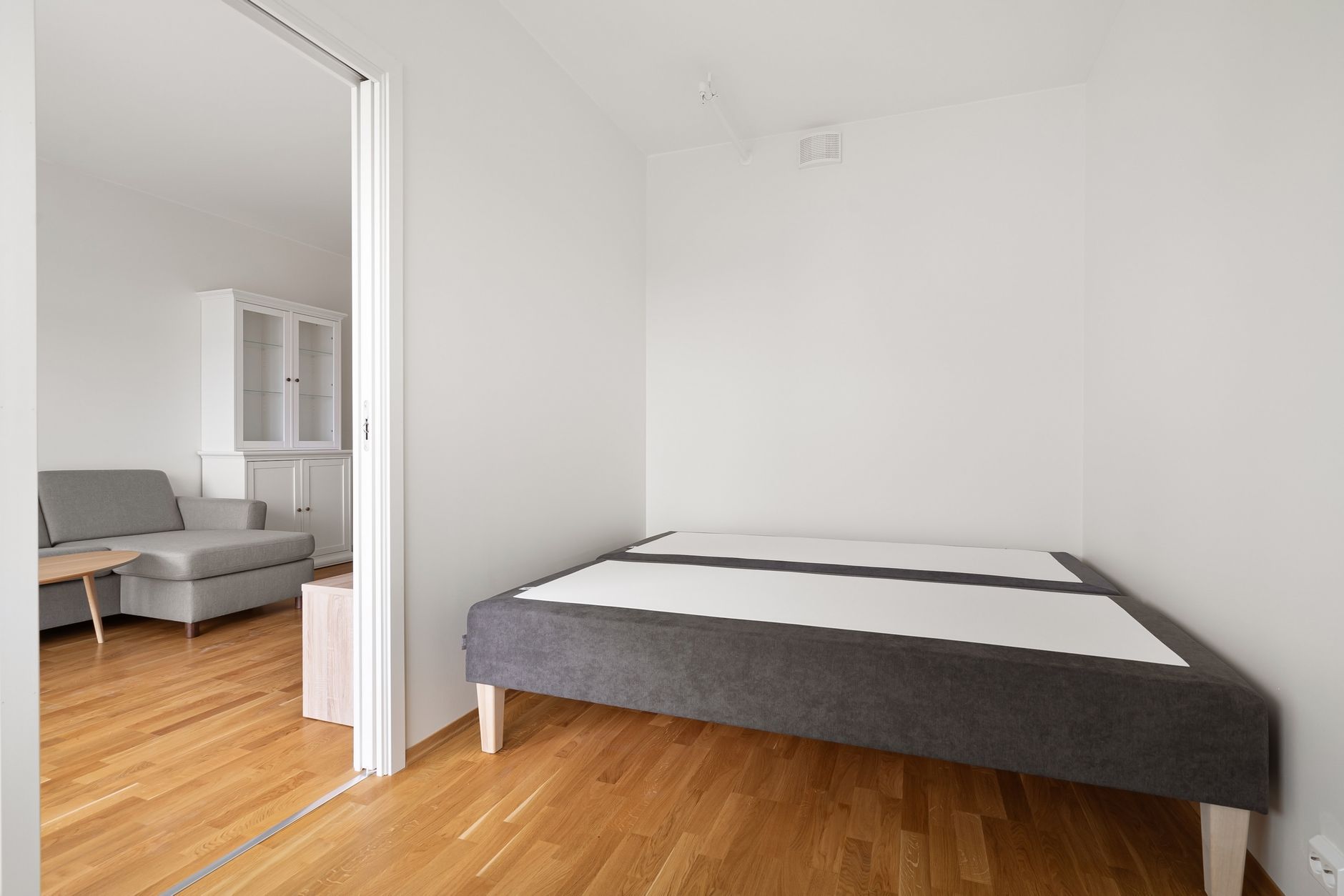 A small bedroom with a bed frame and a sliding door