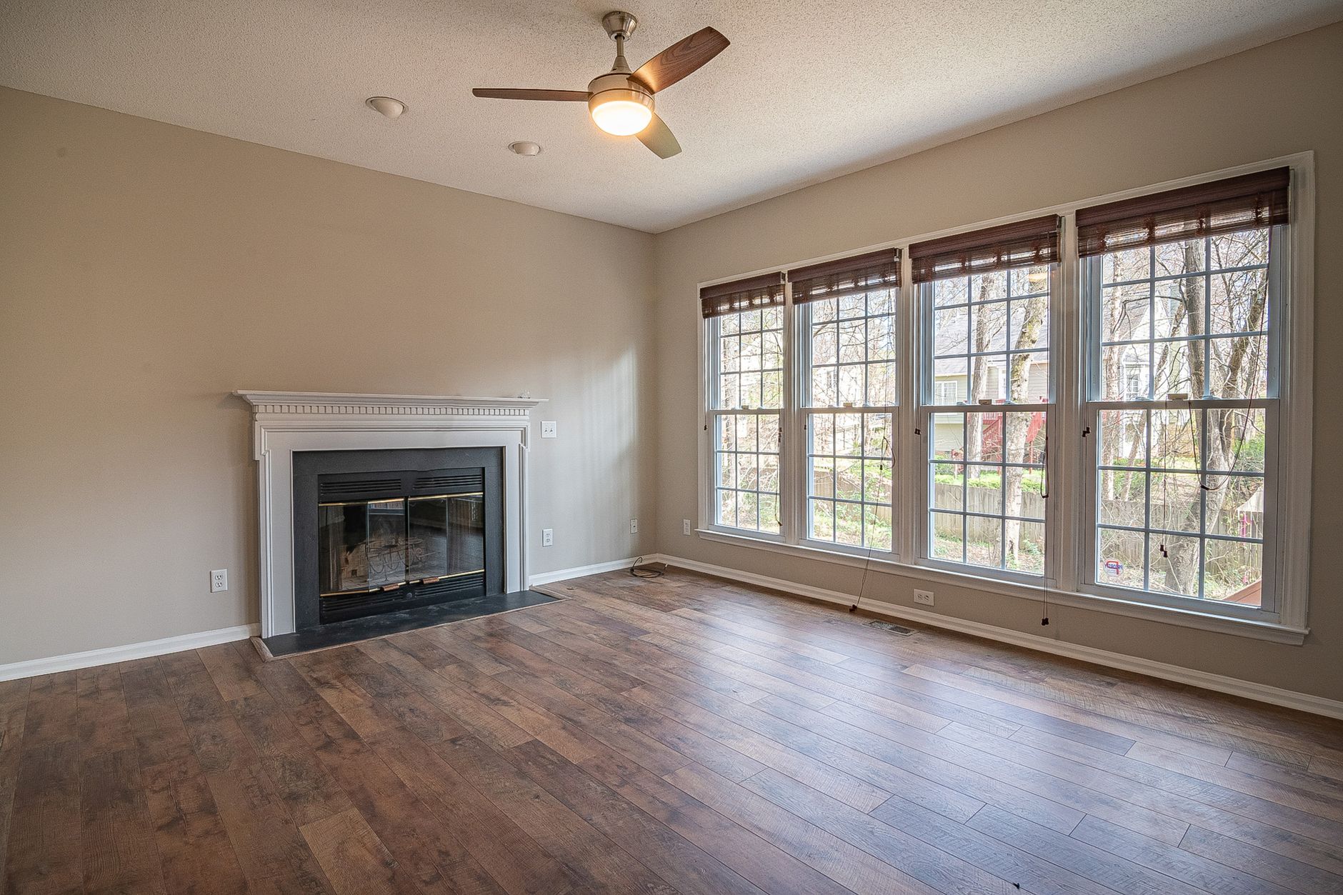 An empty room with a hardwood floor and fireplace