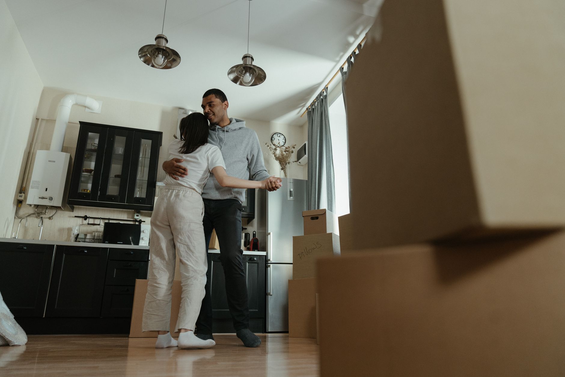 A couple hugging in a kitchen among moving boxes