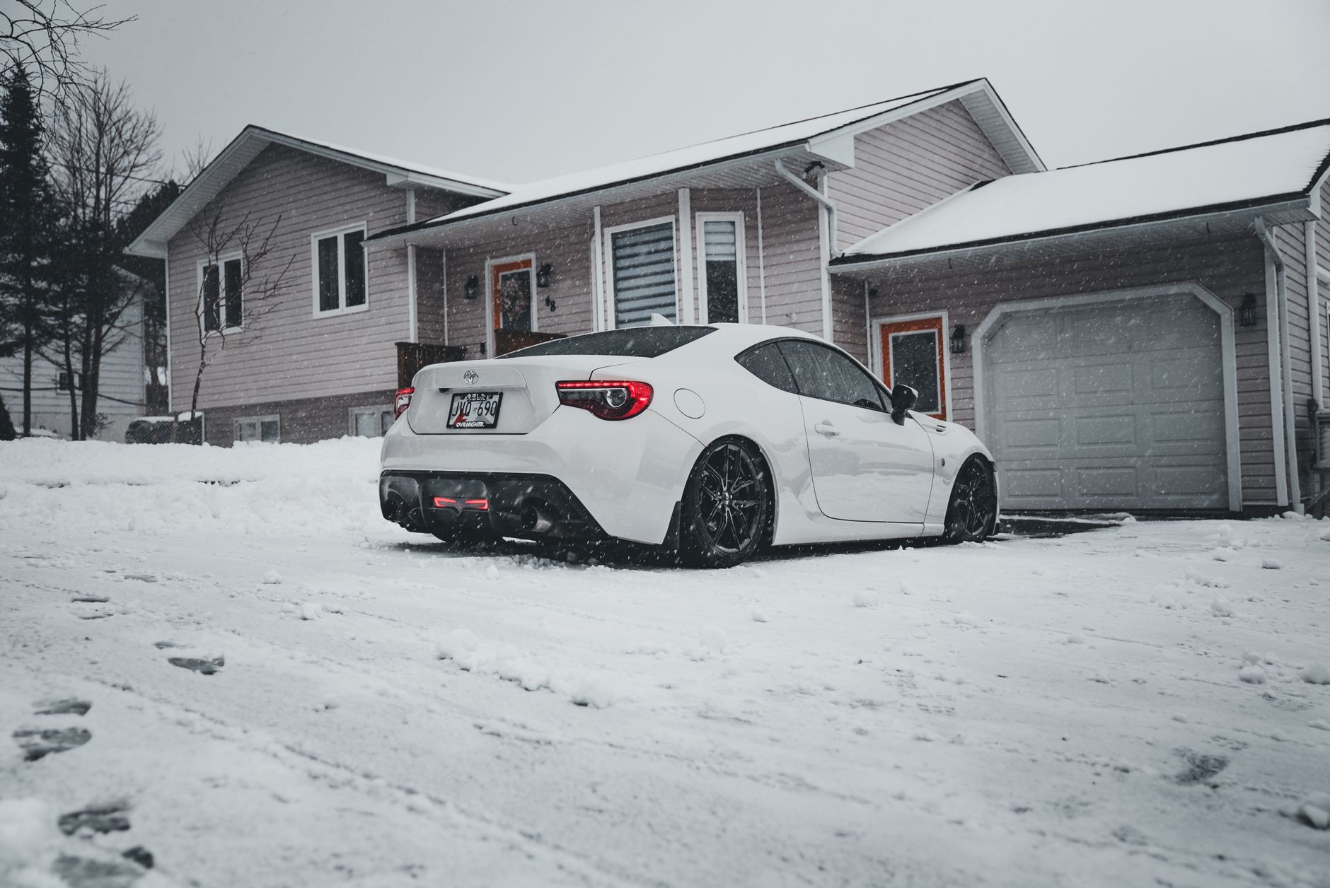 A car parked on a snowy driveway in front of a garage