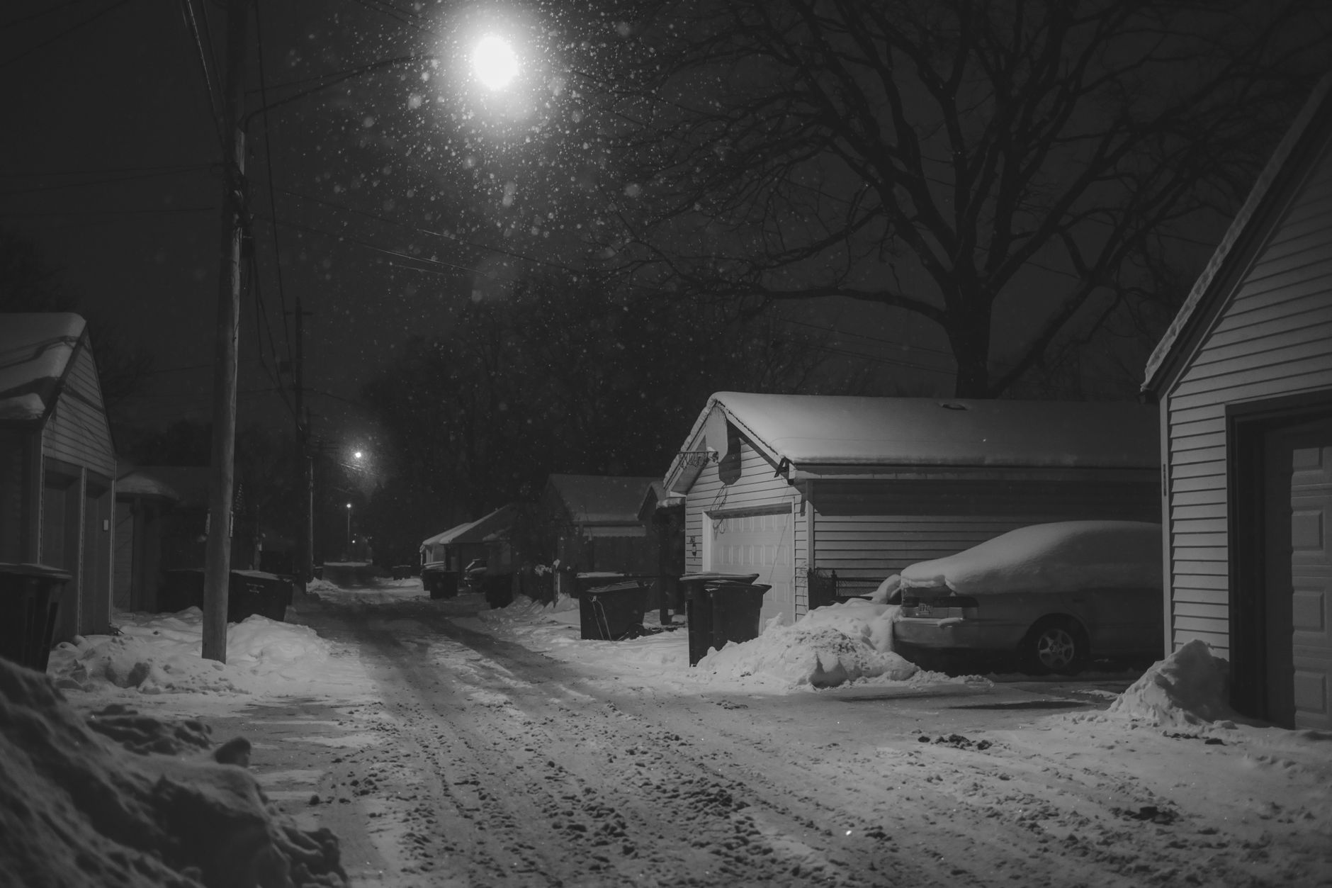 Snow falling on an alley lined with garages