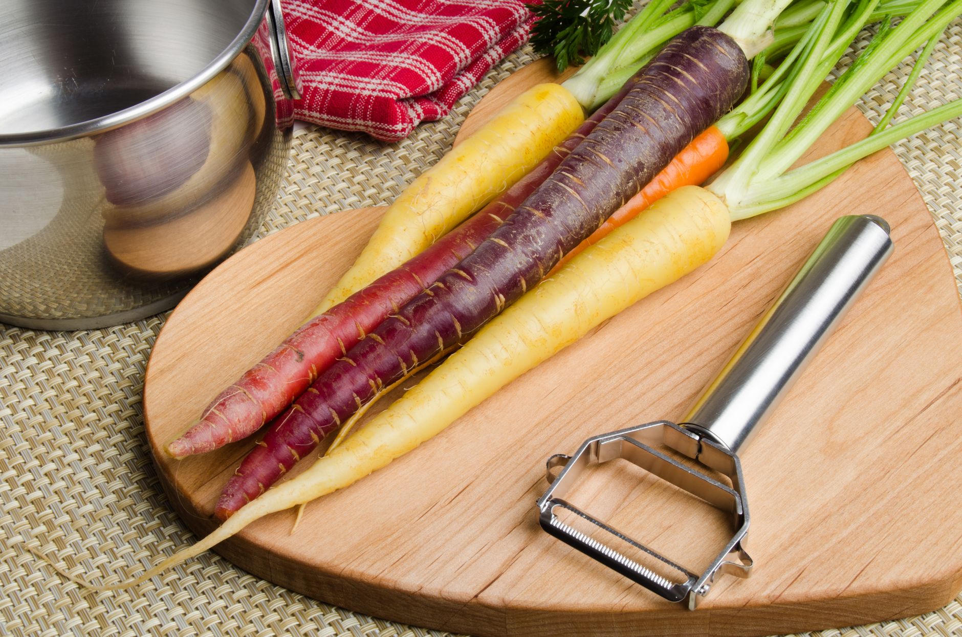 Carrots and a peeler on a cutting board