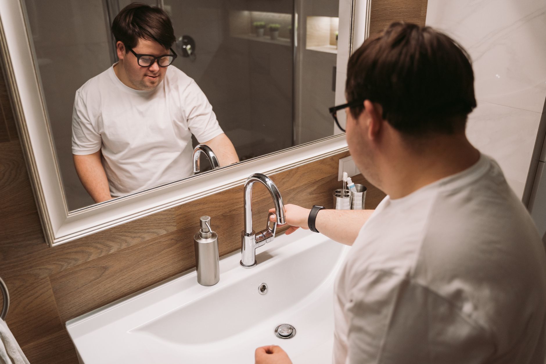 A man washing his hands at a bathroom sink