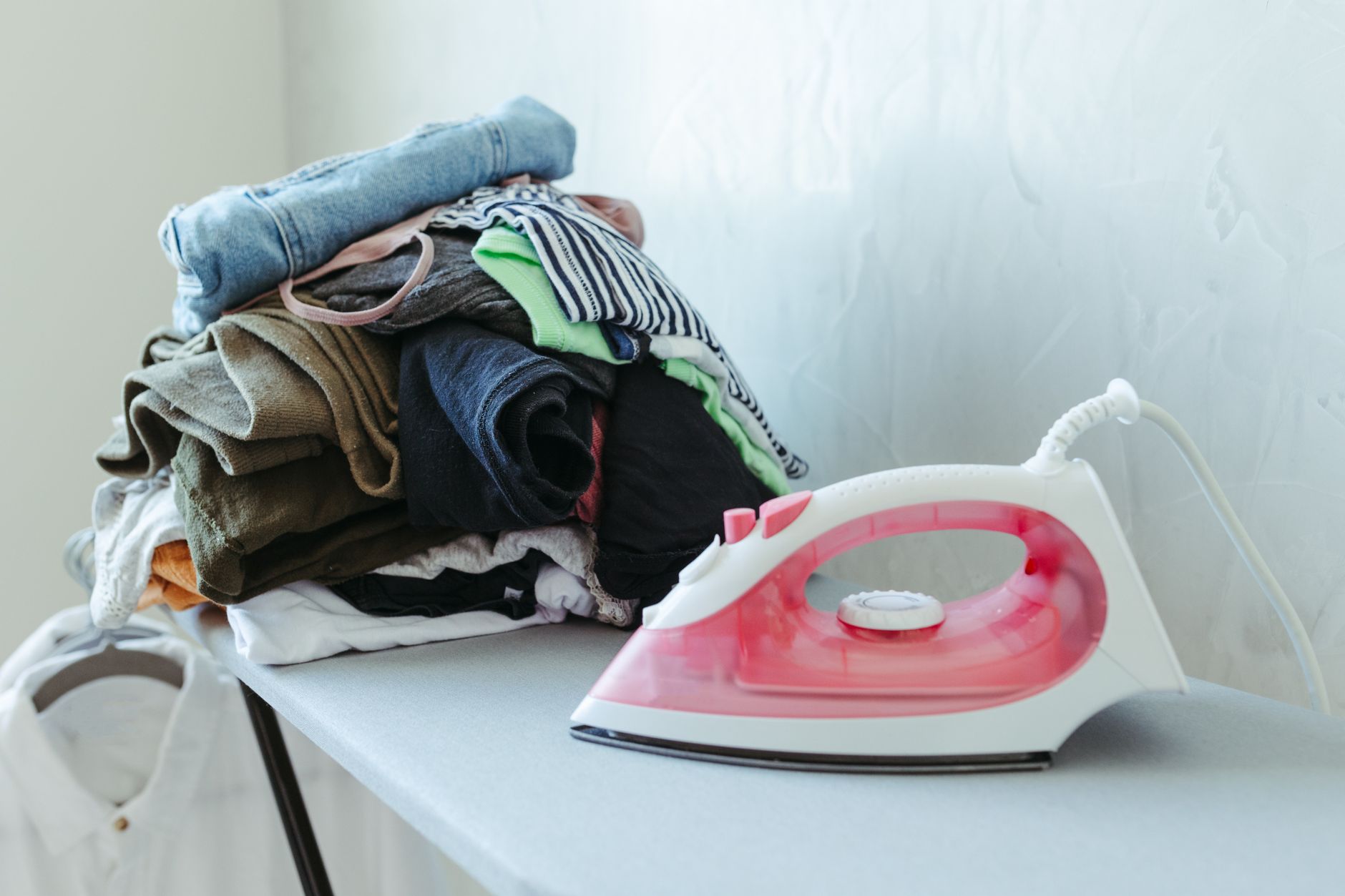 An iron next to a pile of clothes