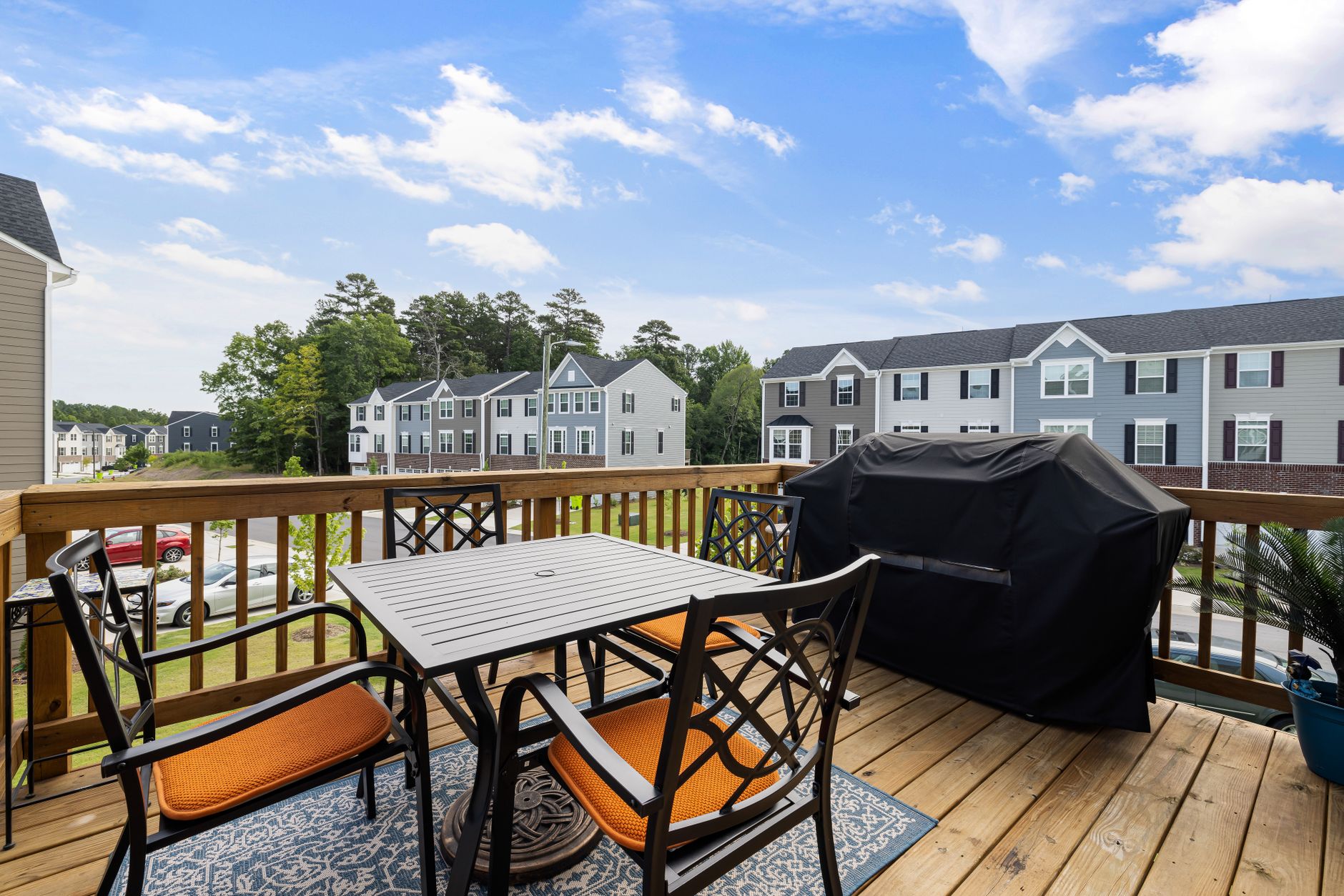 A deck with a covered grill and patio table