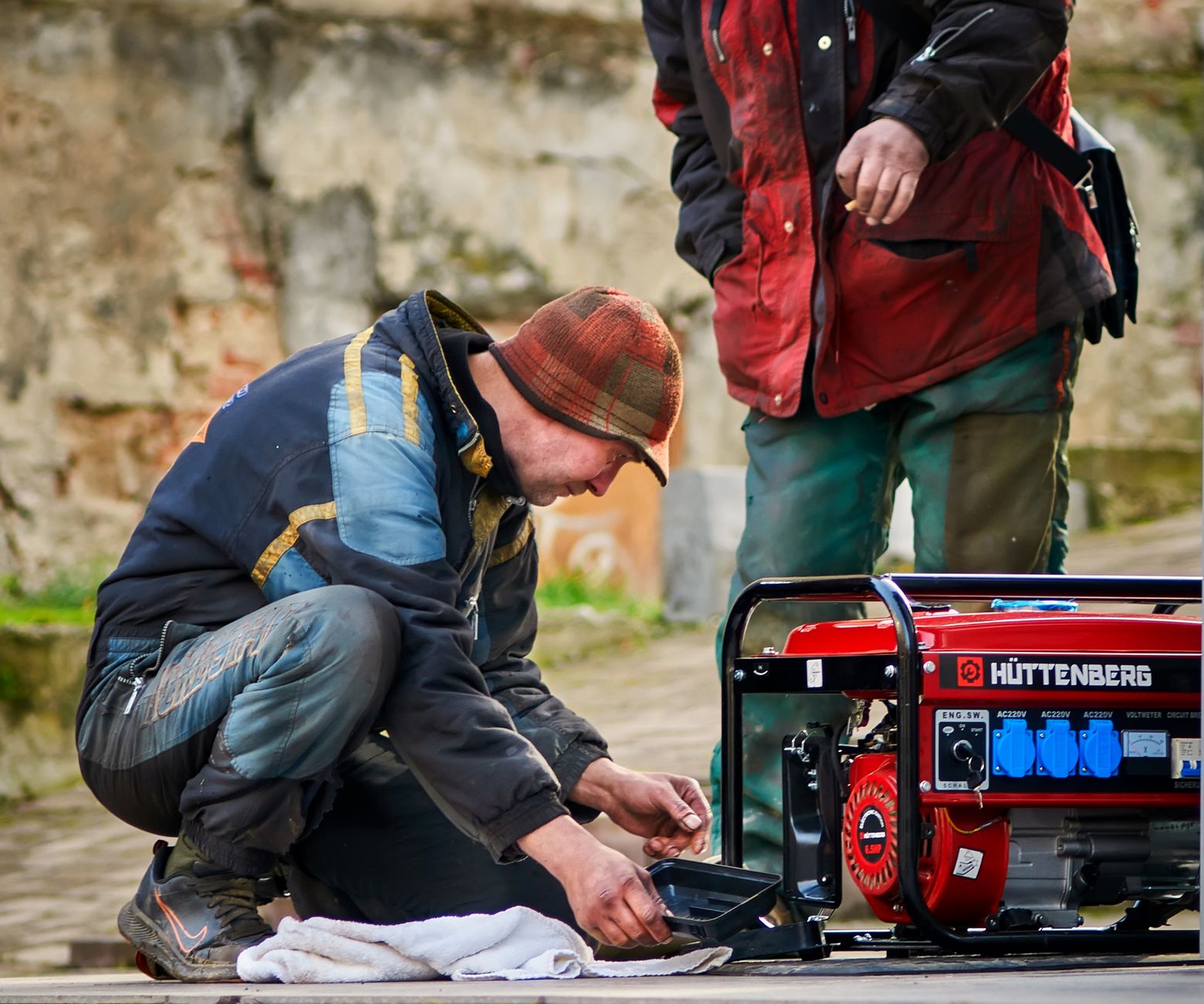 Two men starting a portable generator outdoors