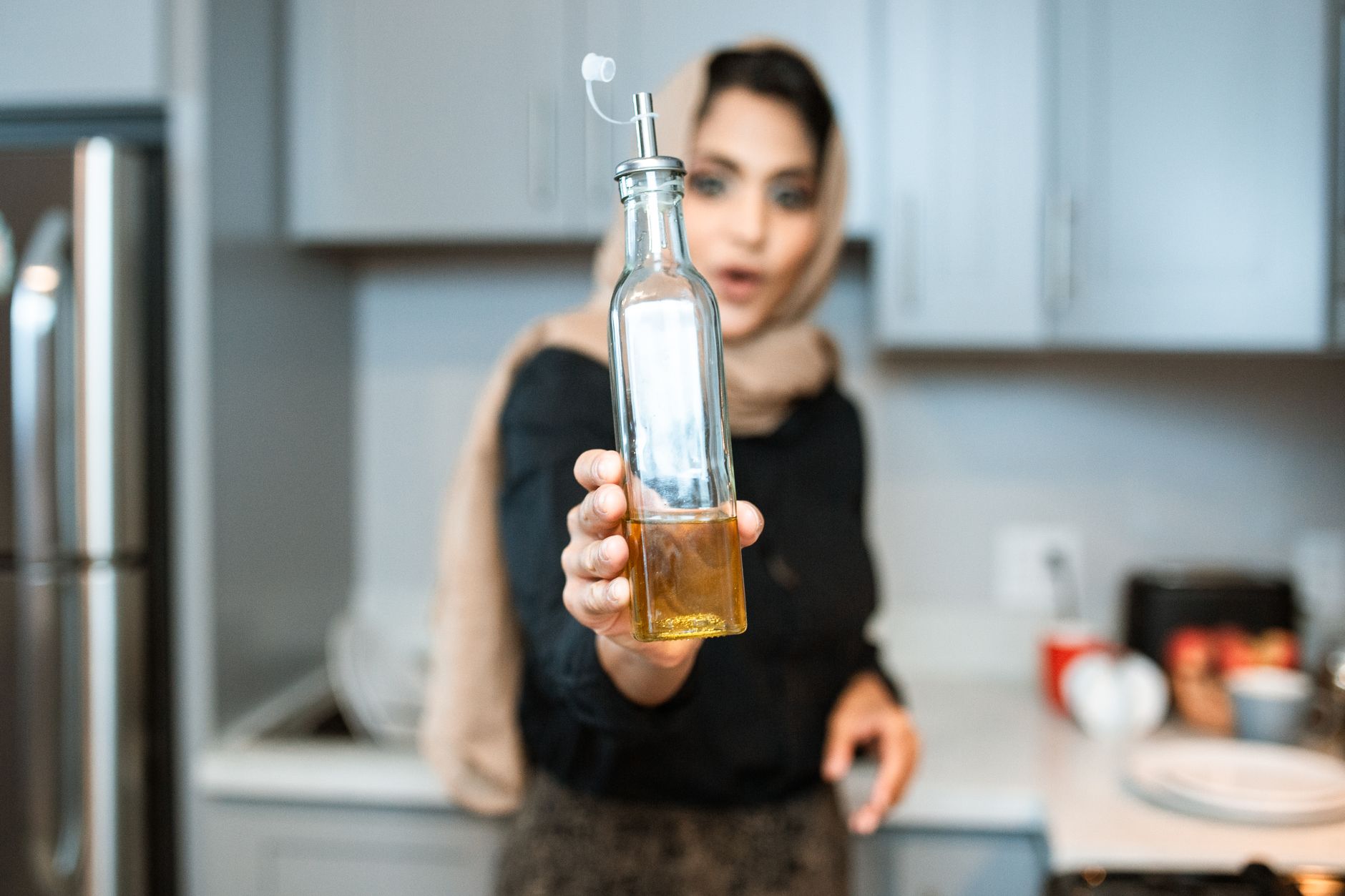 A woman holding a bottle of cooking oil