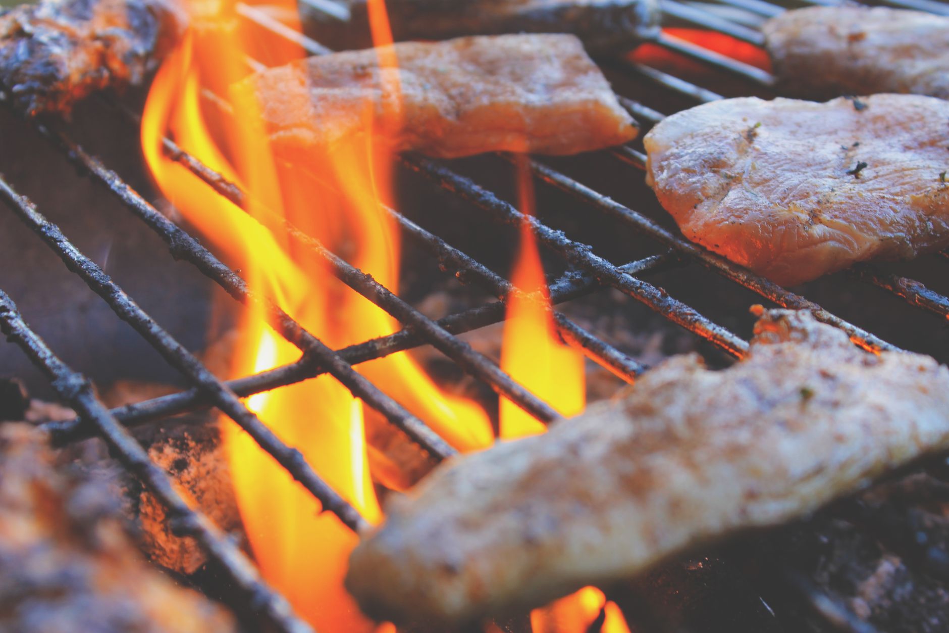 Meat cooking over grill flames
