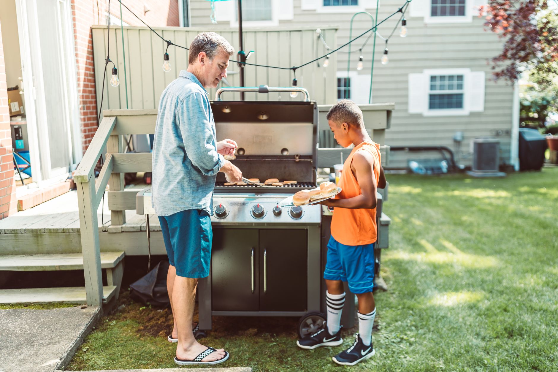 A father and son at a backyard gas grill