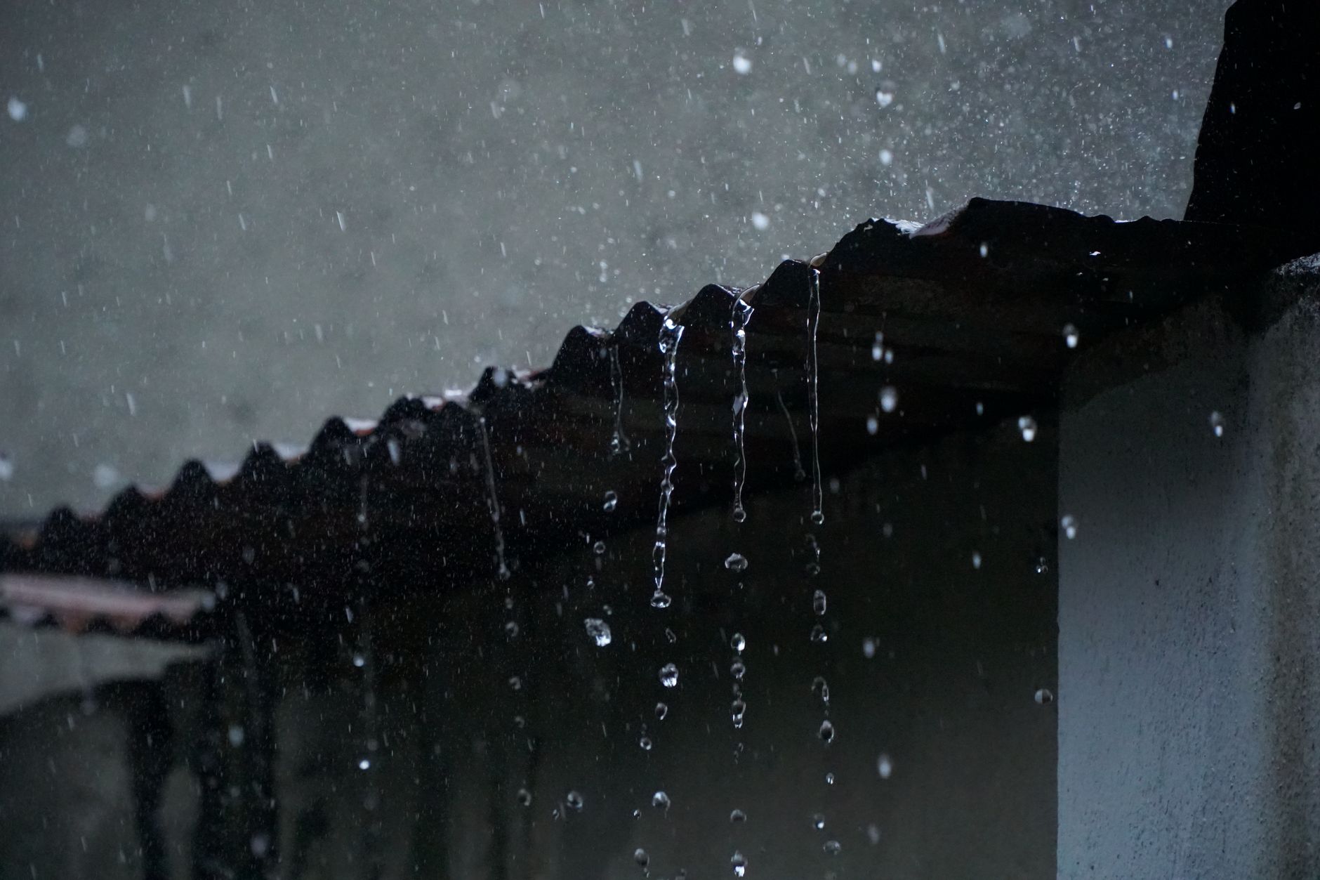 Rainwater dripping off a roof edge