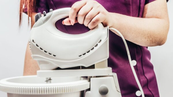 A woman holding a mixer above a bowl