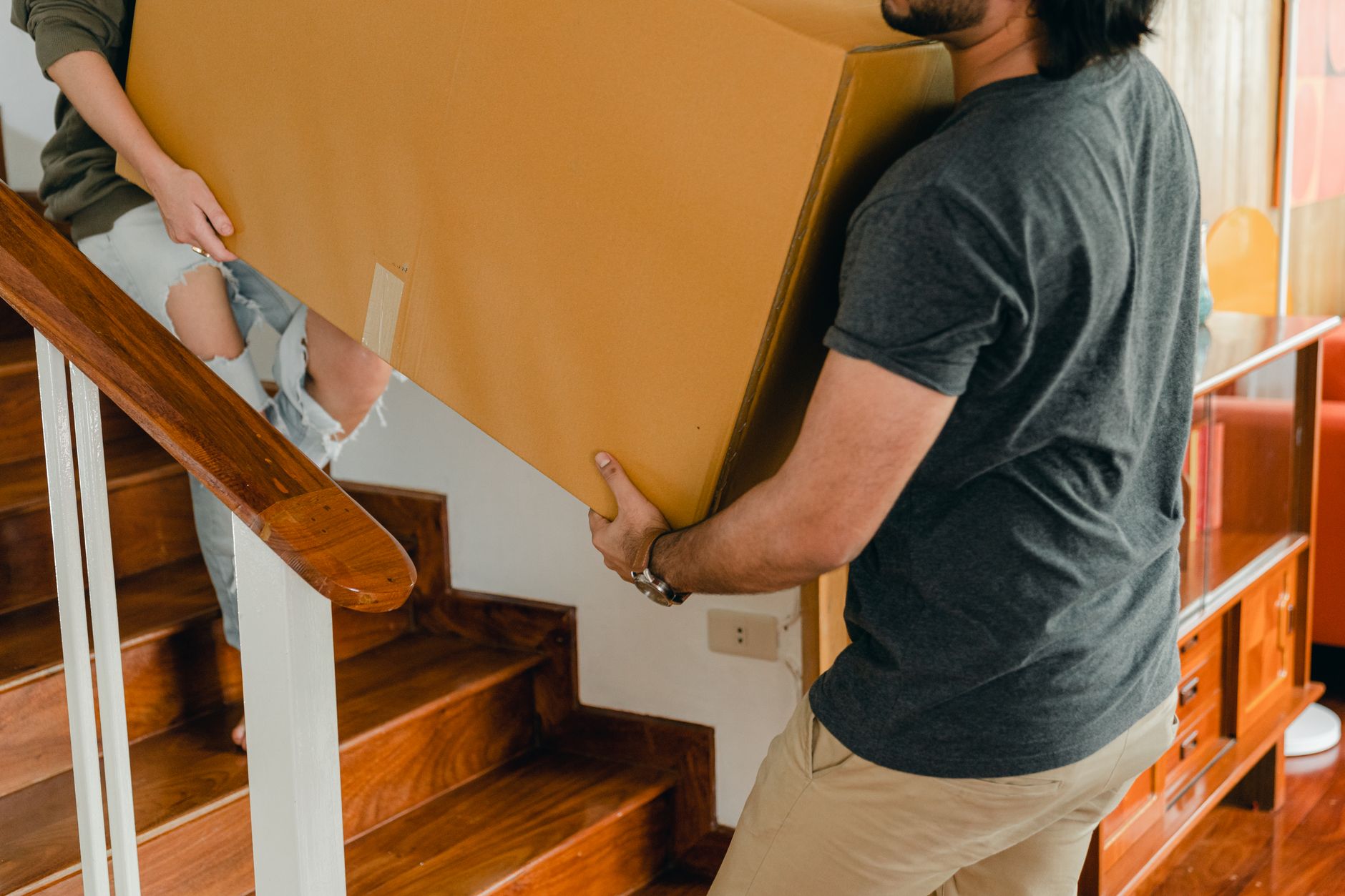 Two people carrying a large box up stairs