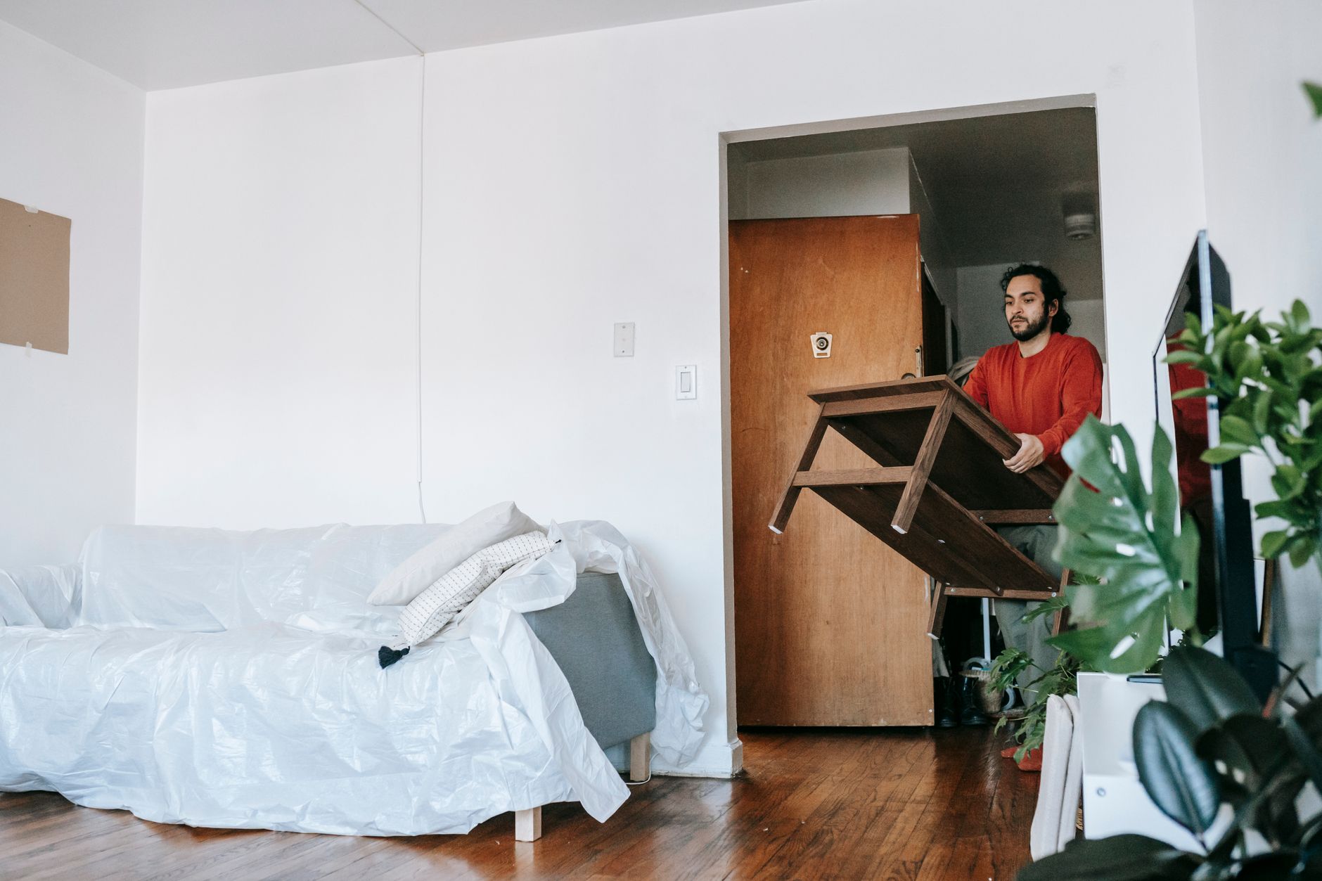 A man carrying a table through an apartment