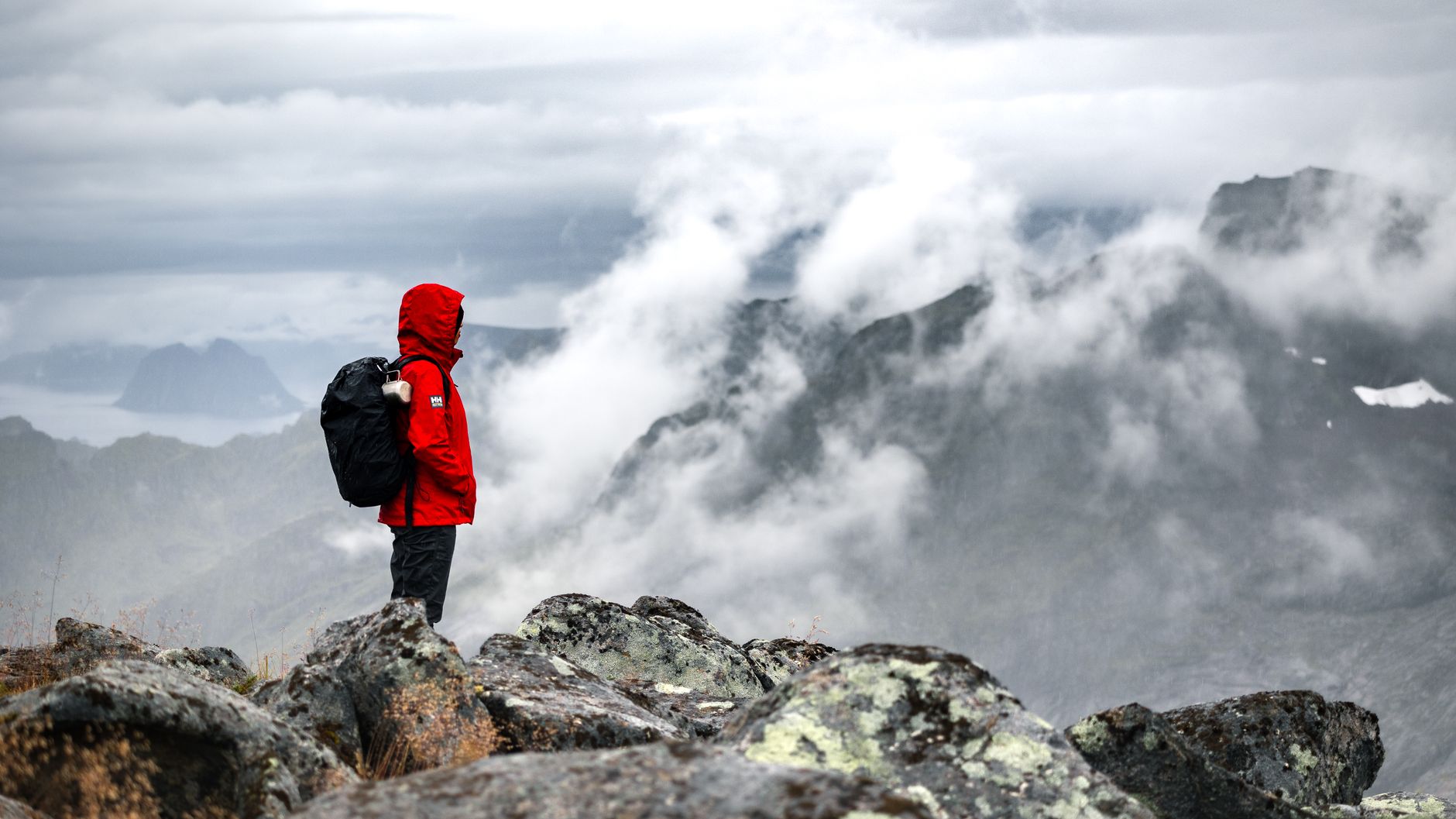 A hiker in a red jacket above the clouds