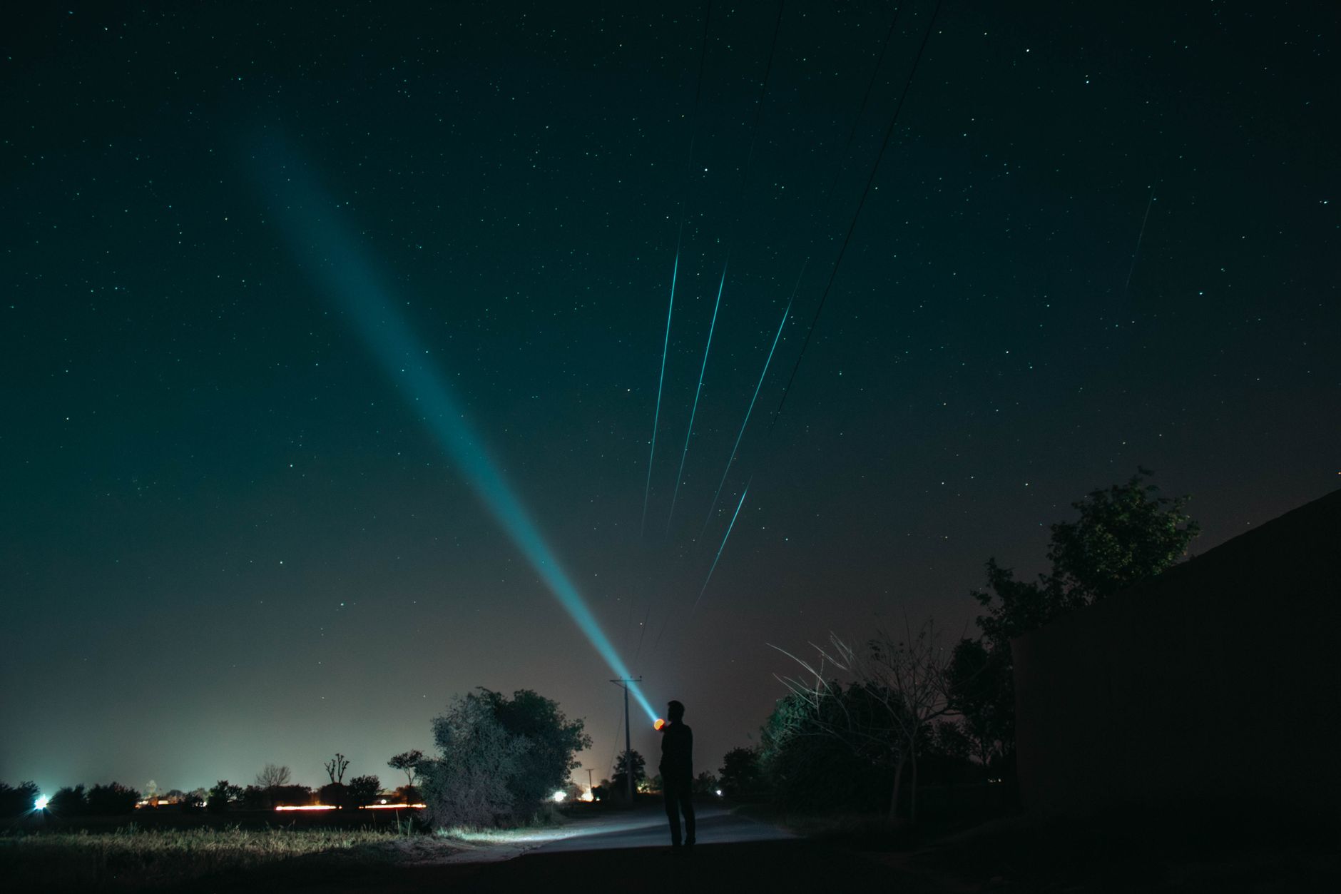 A person shining a bright beam into the night sky