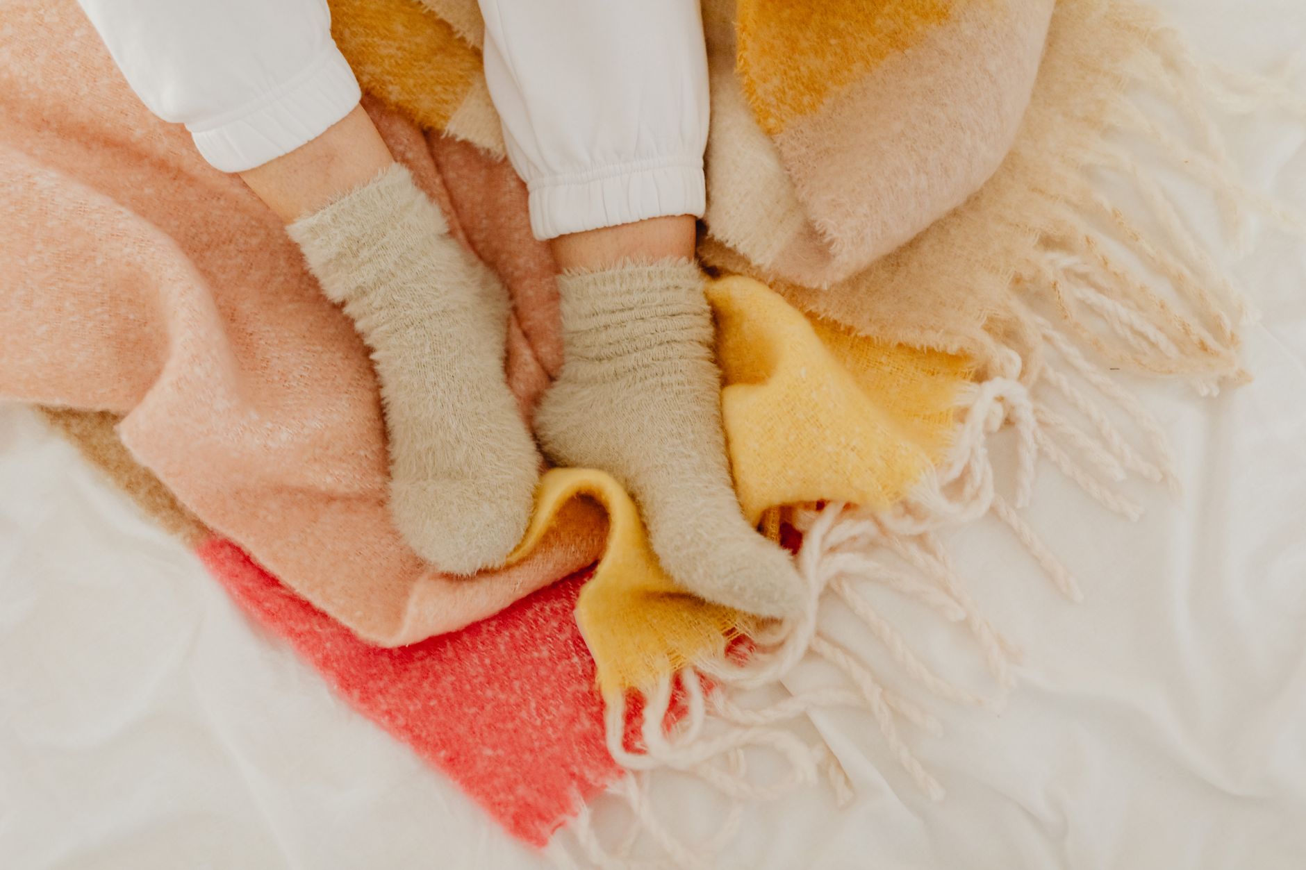 Feet in wool socks resting under a blanket