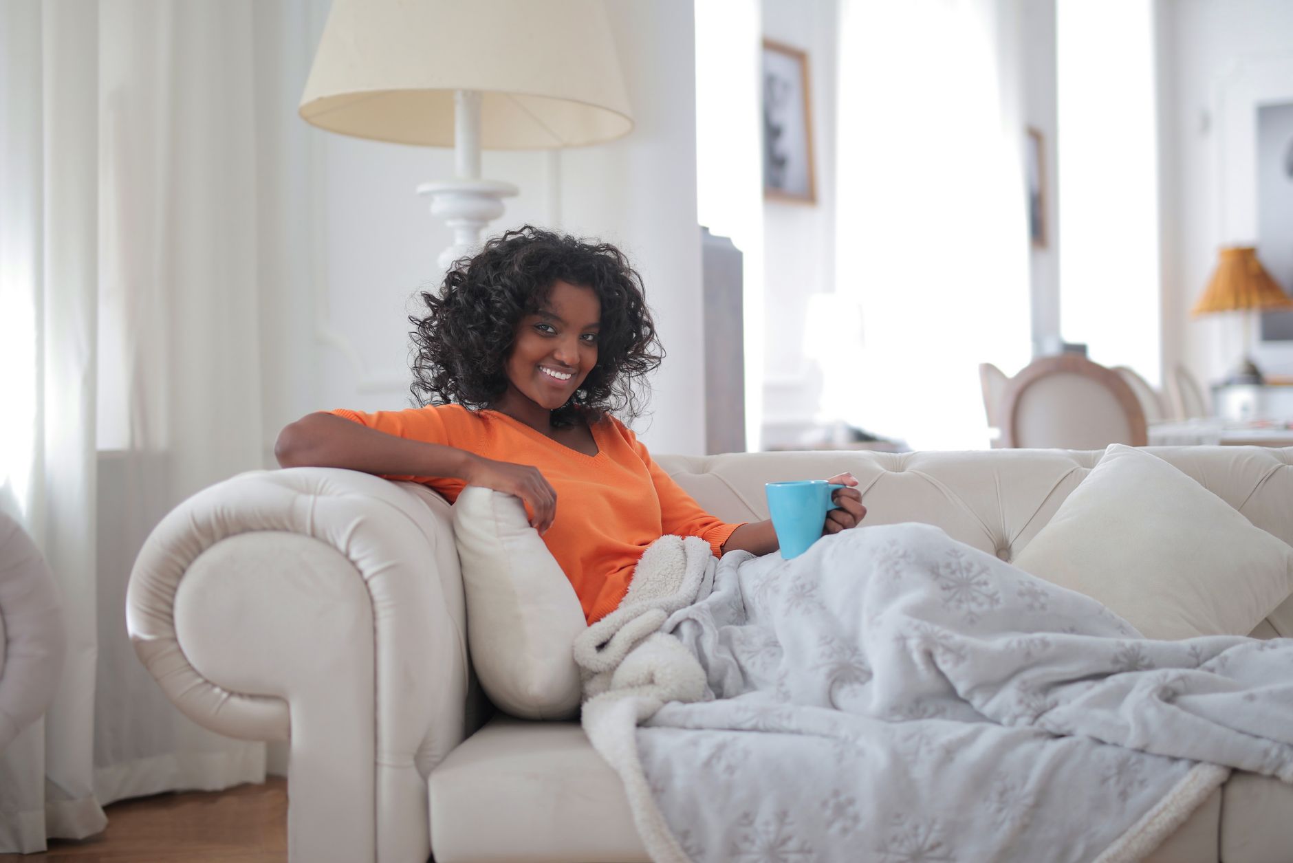 A person relaxing on a sofa under a blanket