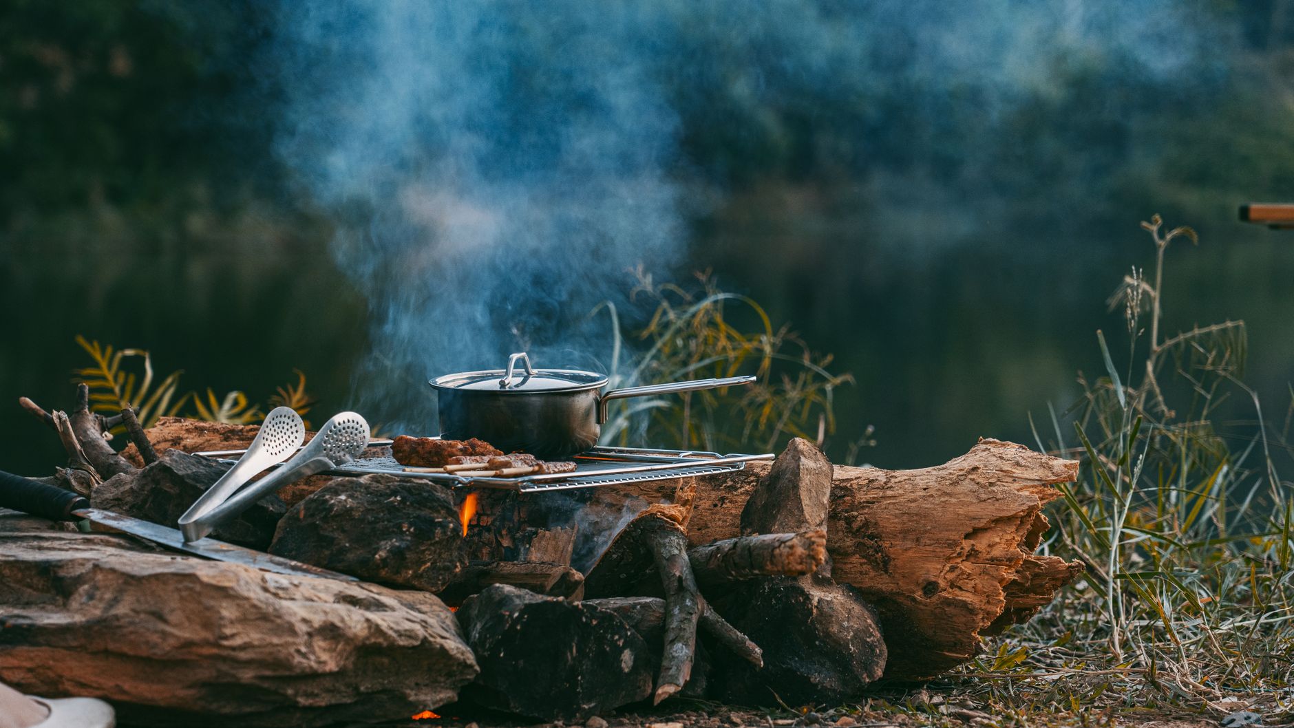 A pot over a campfire by a lake
