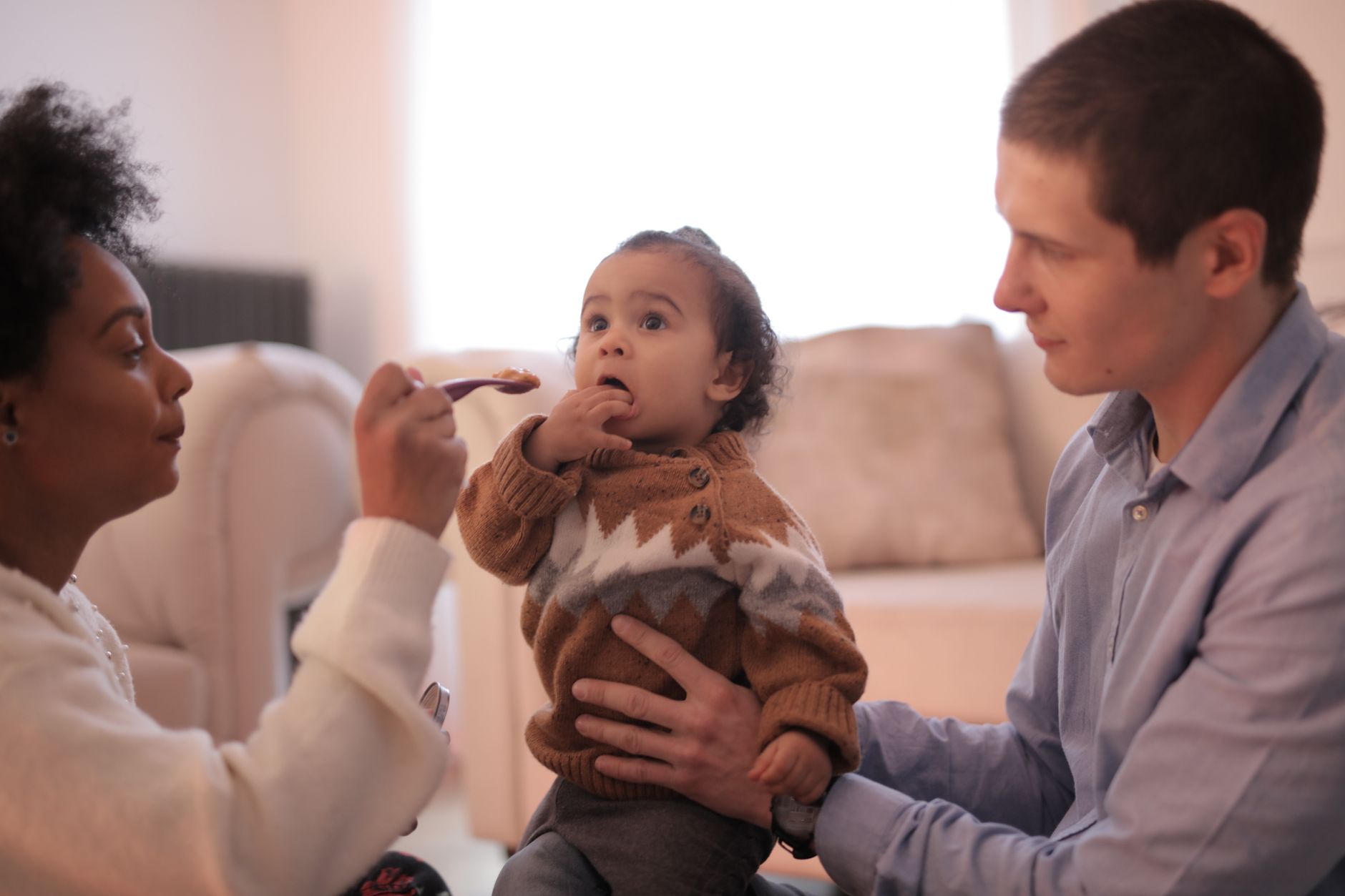 A parent feeding a baby with a spoon at mealtime