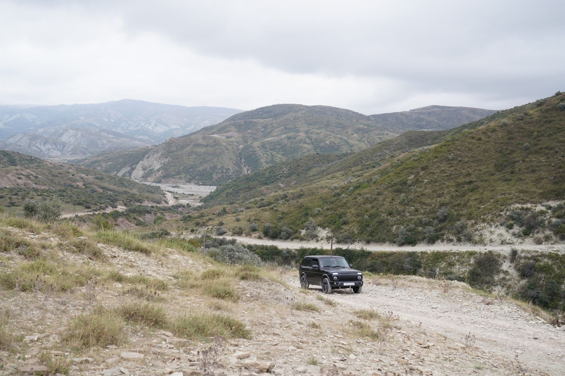 An SUV on a gravel road in the hills