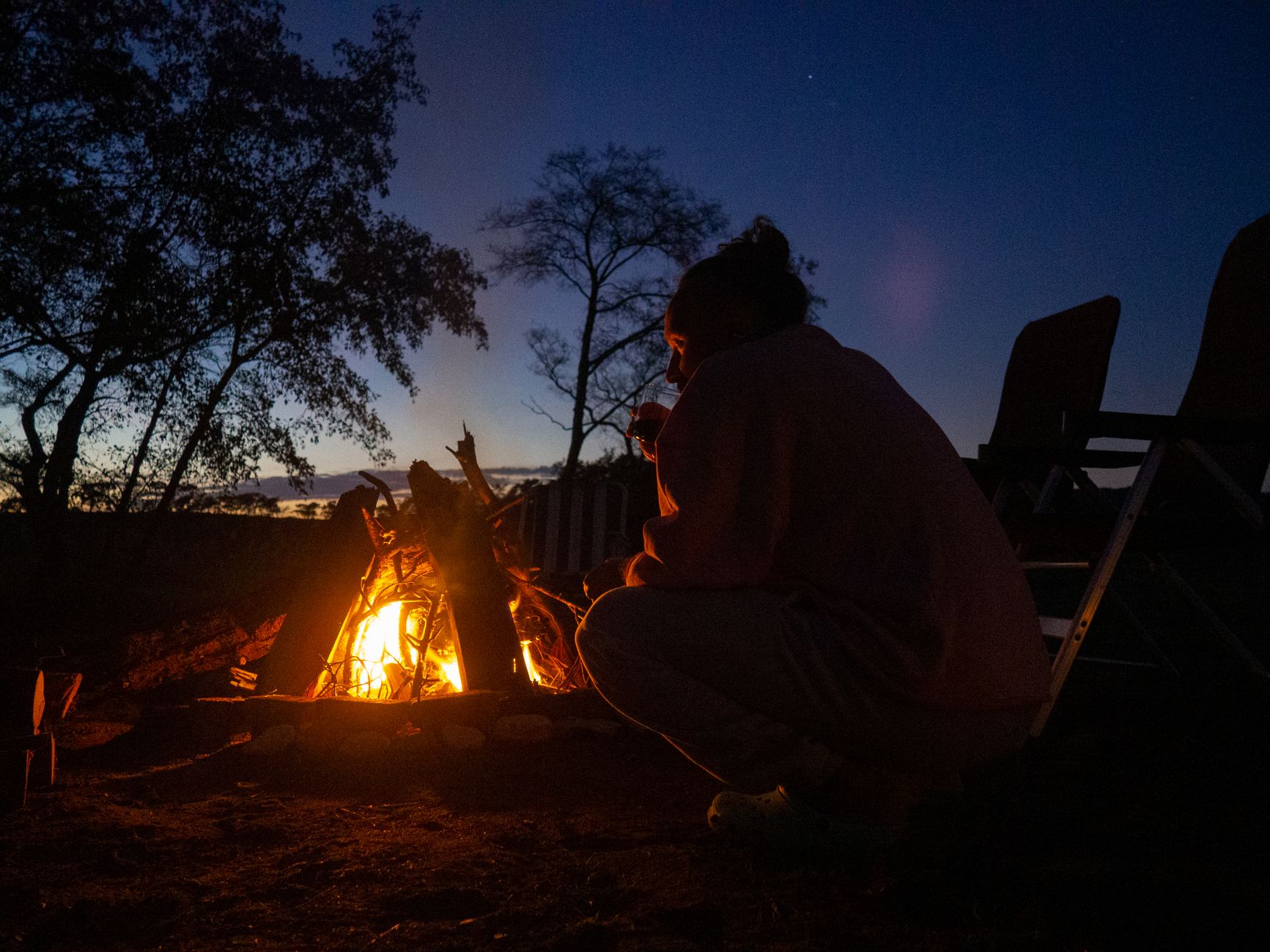 A person by a campfire at dusk