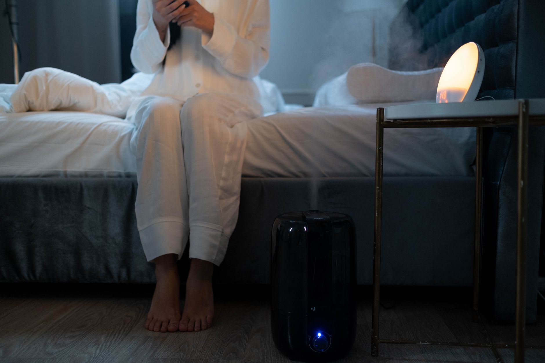 A humidifier on the floor beside a bed