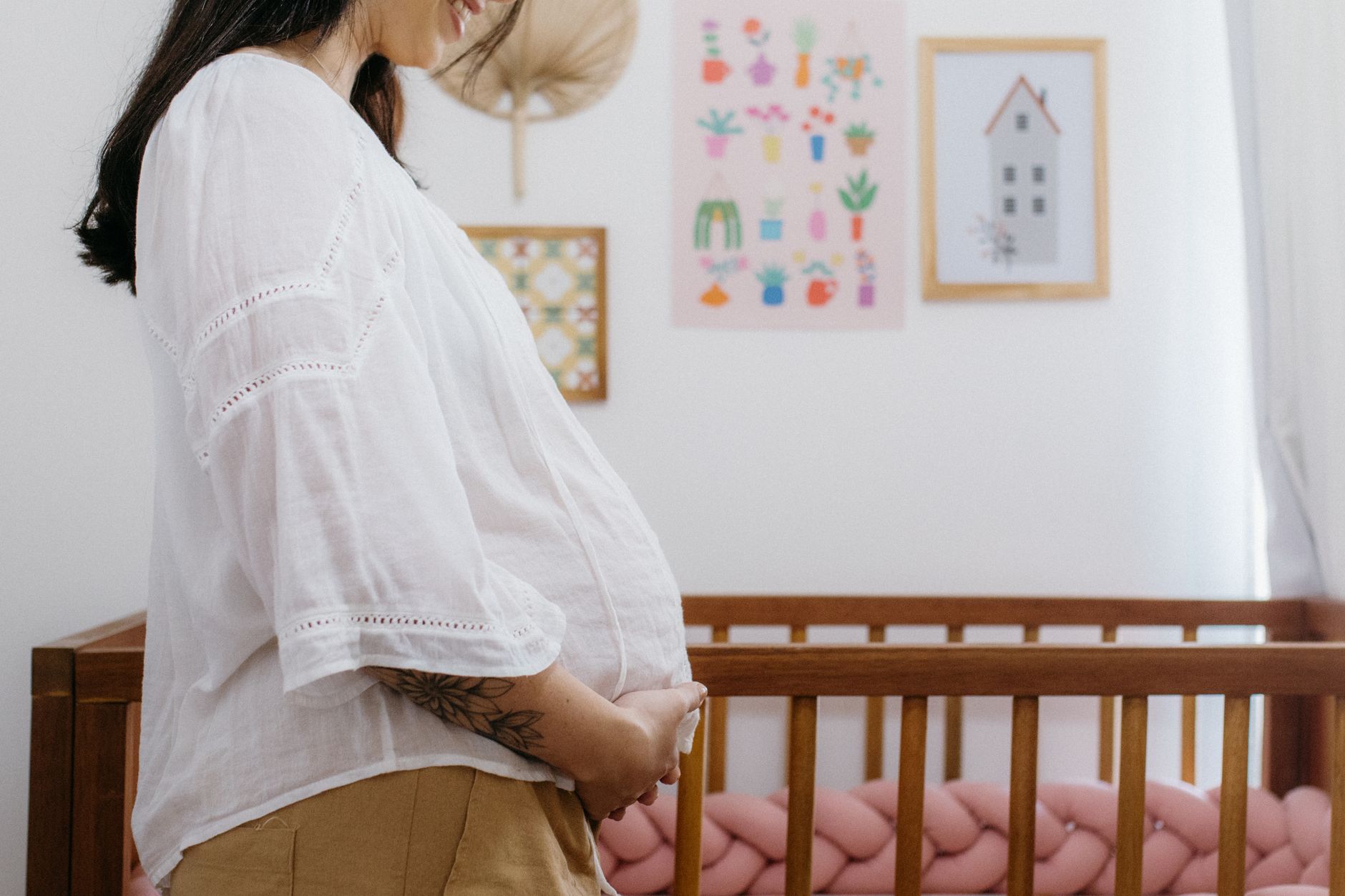 A pregnant woman standing by a crib in a nursery