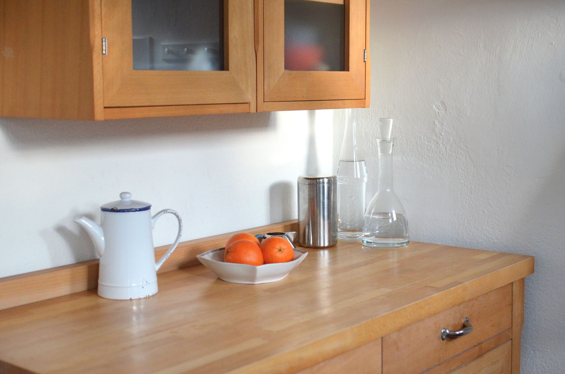 A wooden kitchen counter with a jug and oranges