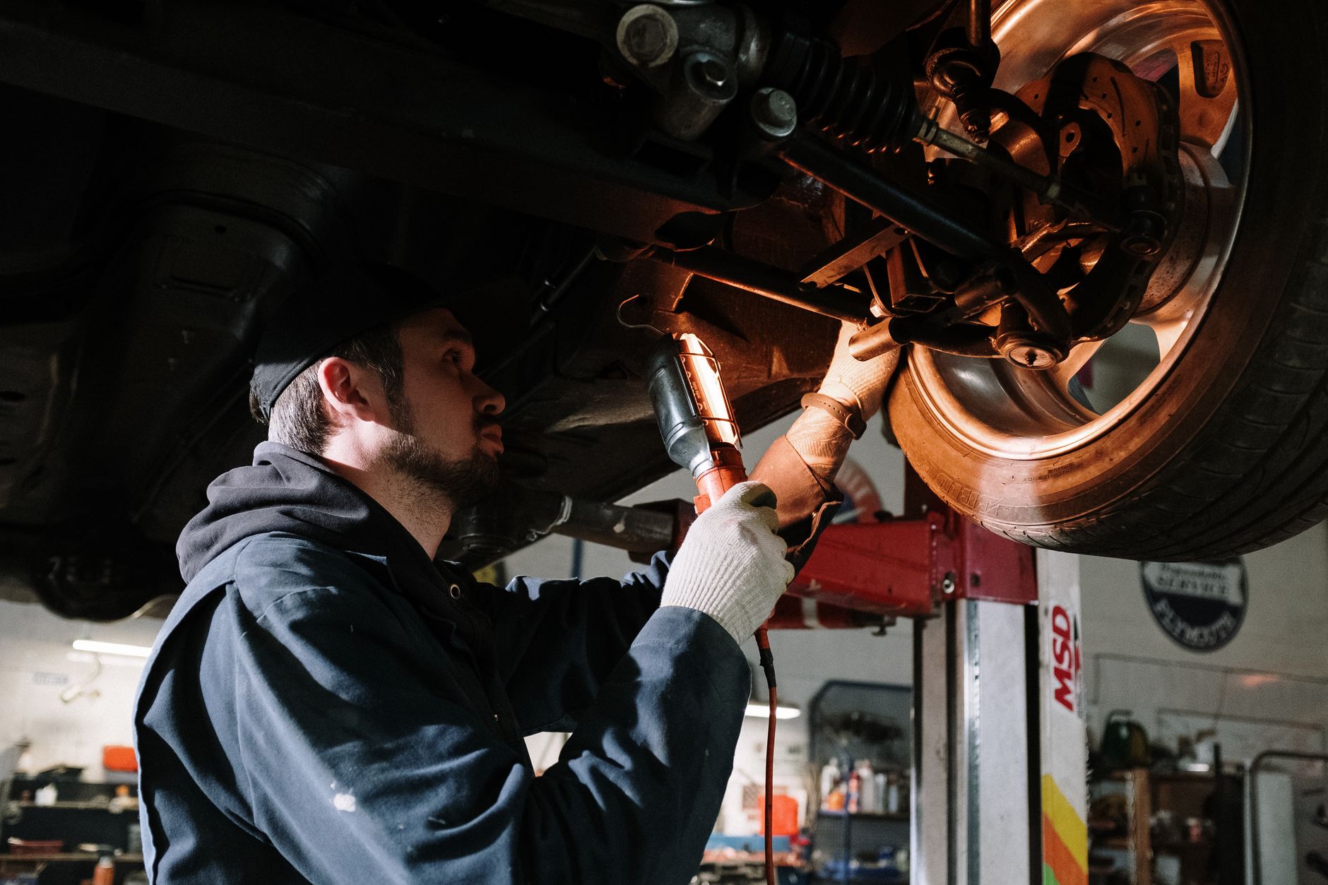 A mechanic working under a raised car