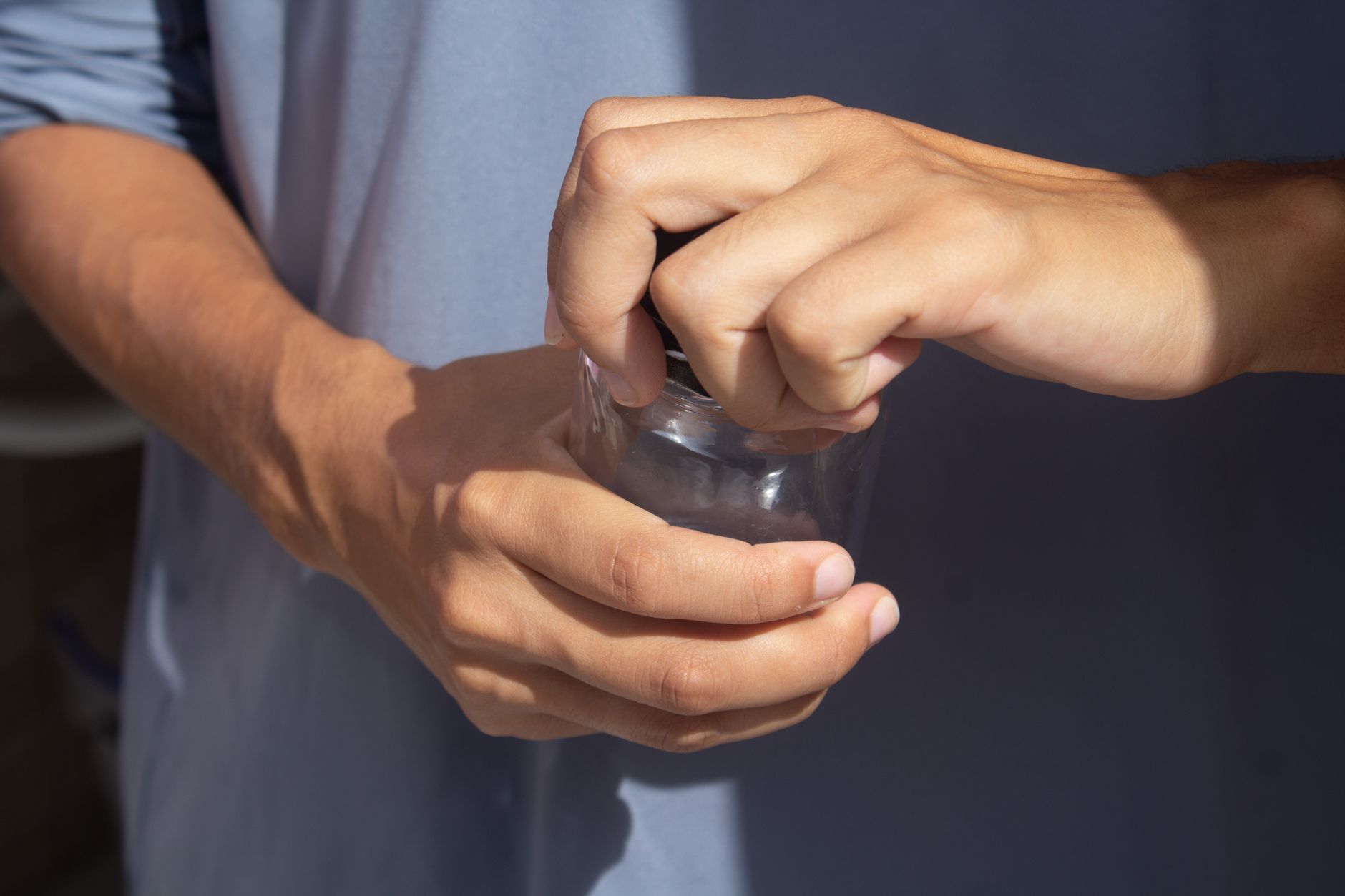 Hands twisting the lid of a small jar