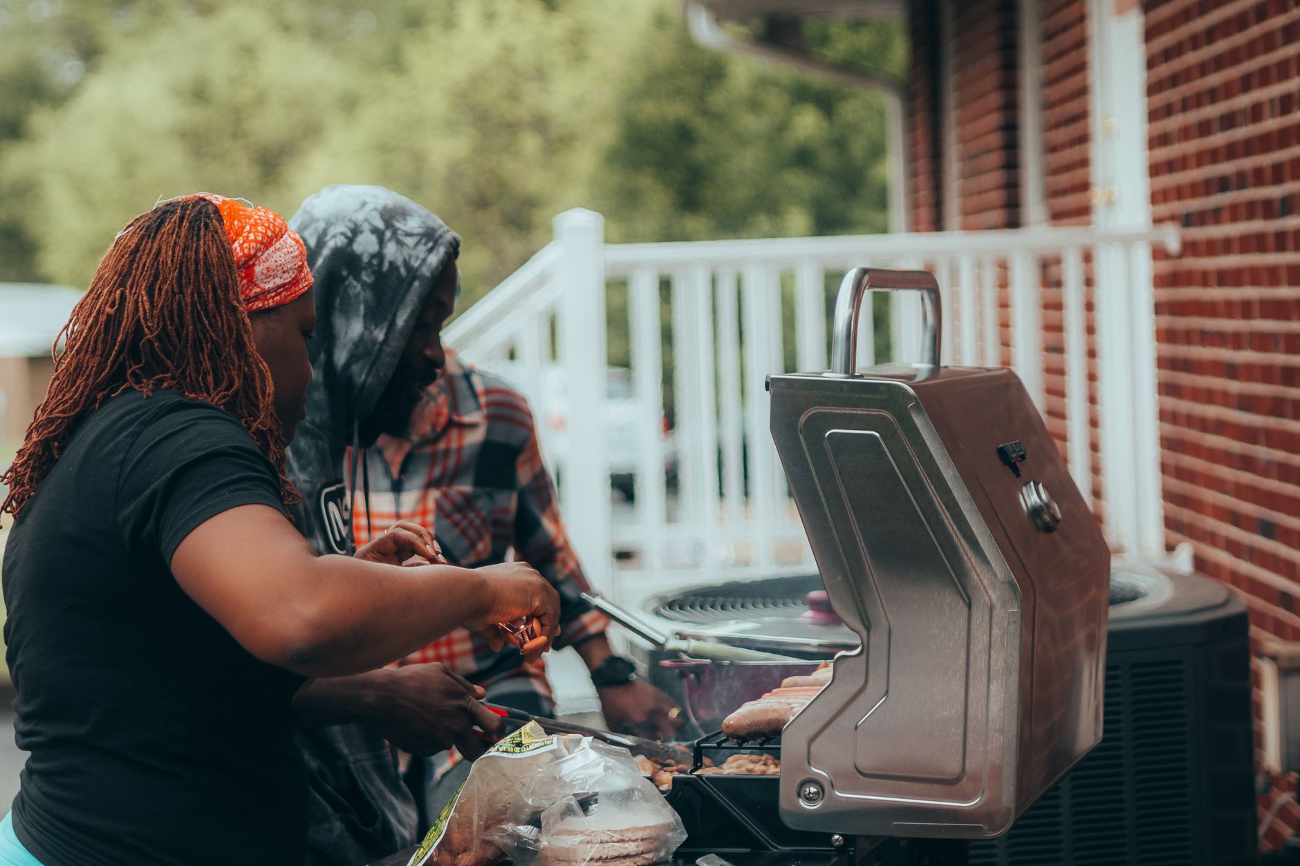 Two people cooking on a portable gas grill
