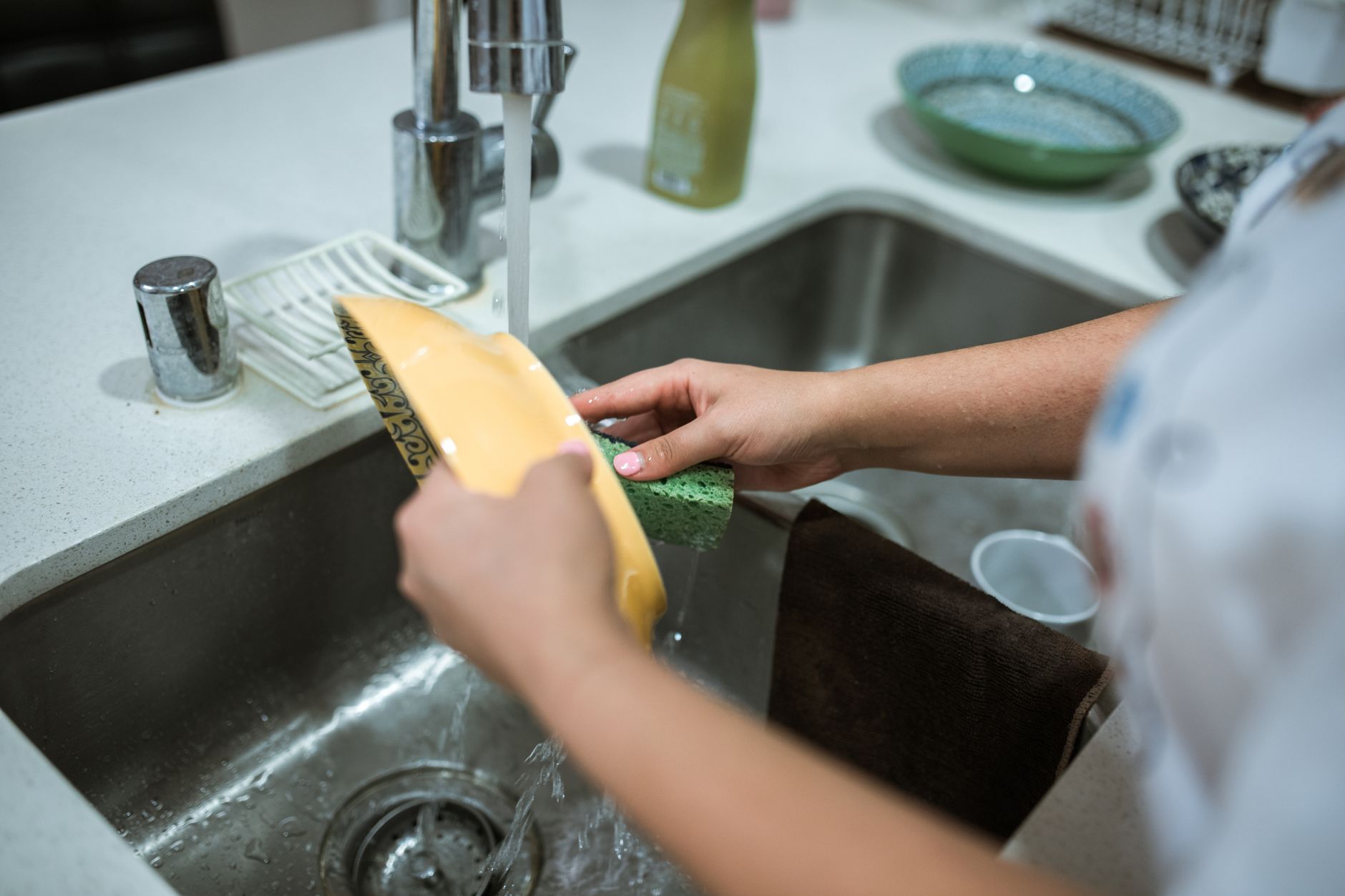 Dishes being rinsed in a kitchen sink
