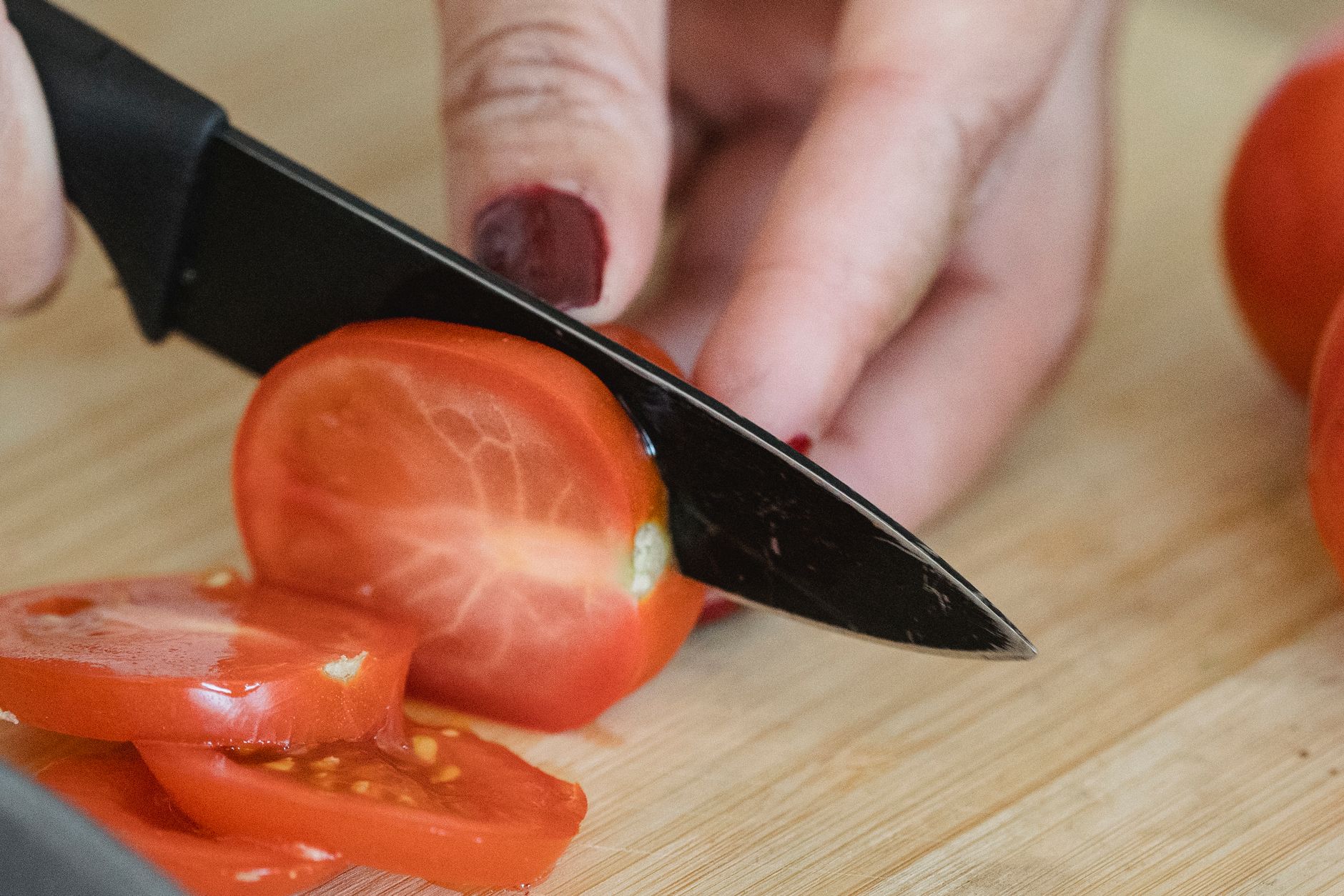 A tomato being sliced on a cutting board