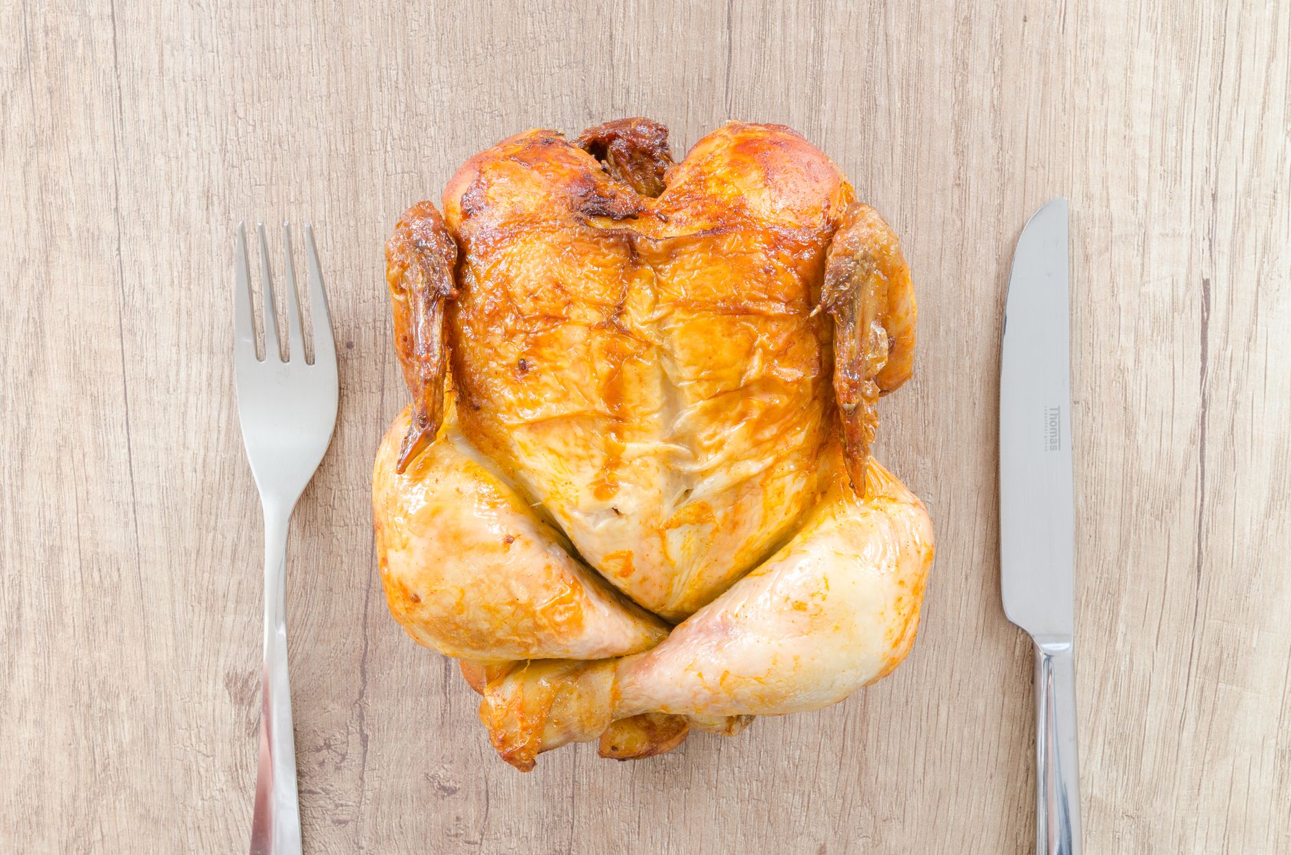 A roasted chicken with a fork and knife