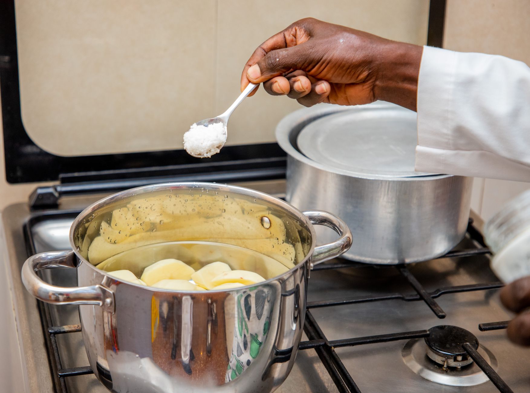 Seasoning a pot of potatoes on a gas stove