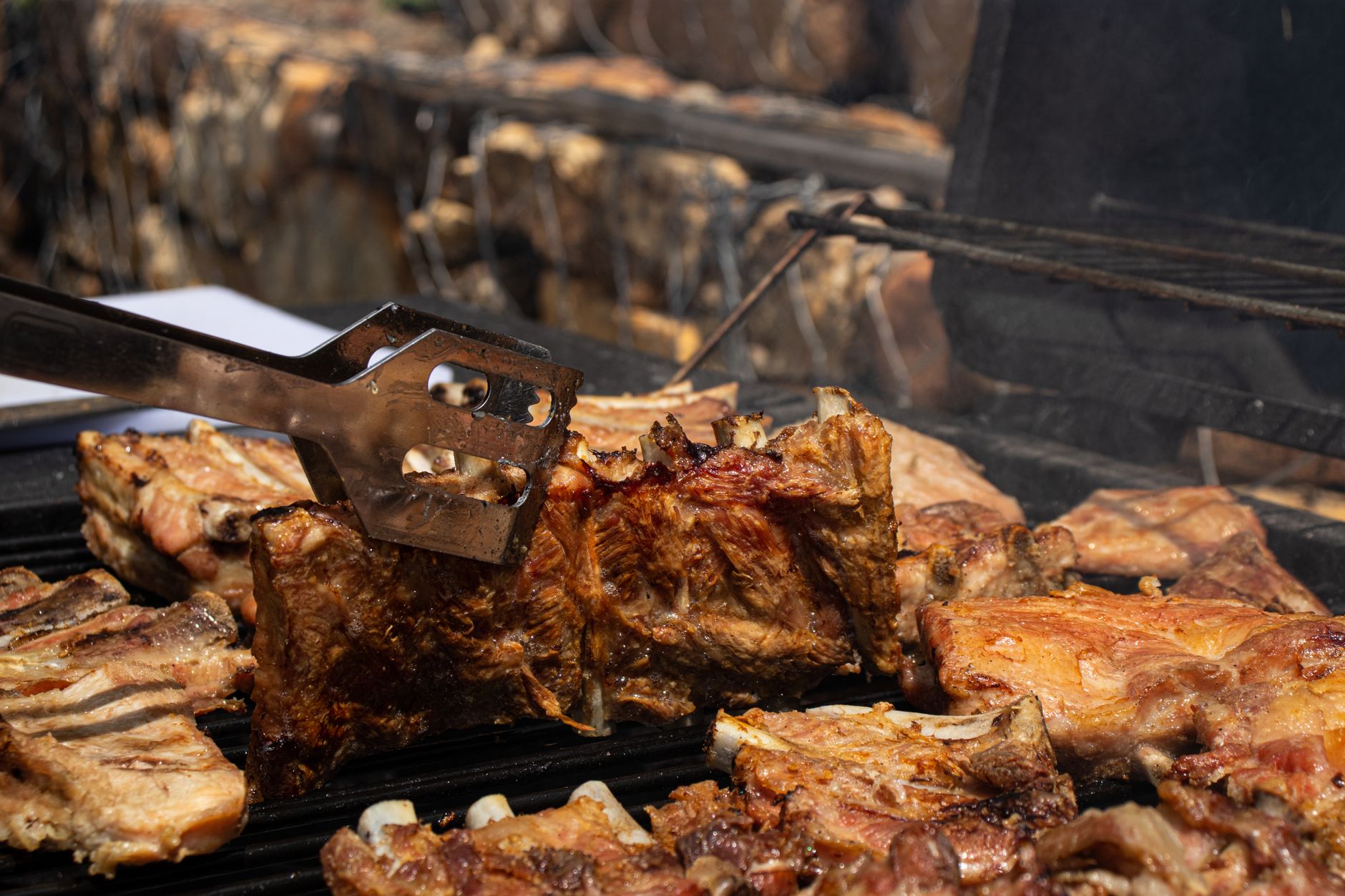 Turning meat on a large grill with tongs