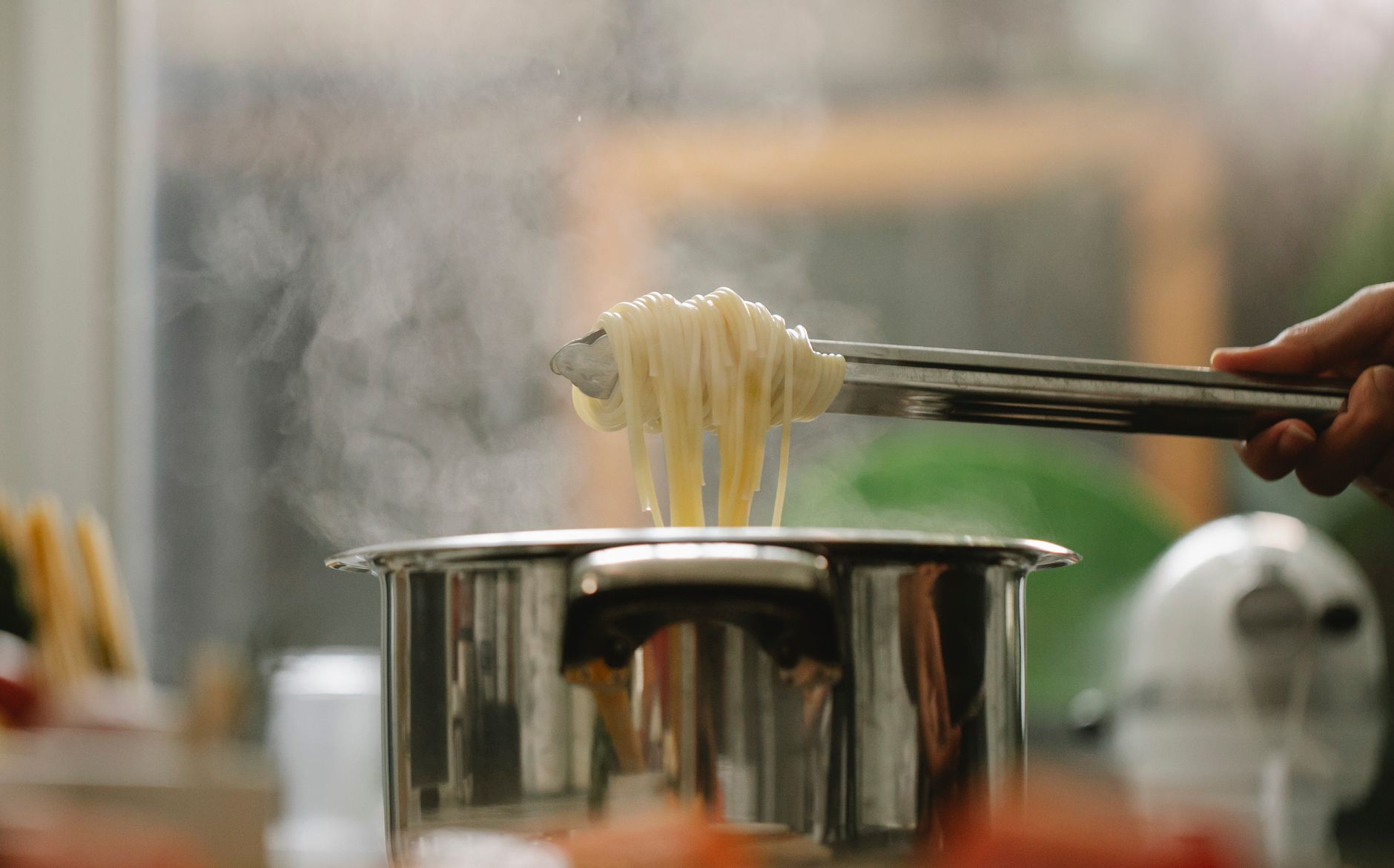 Lifting noodles from a pot with tongs