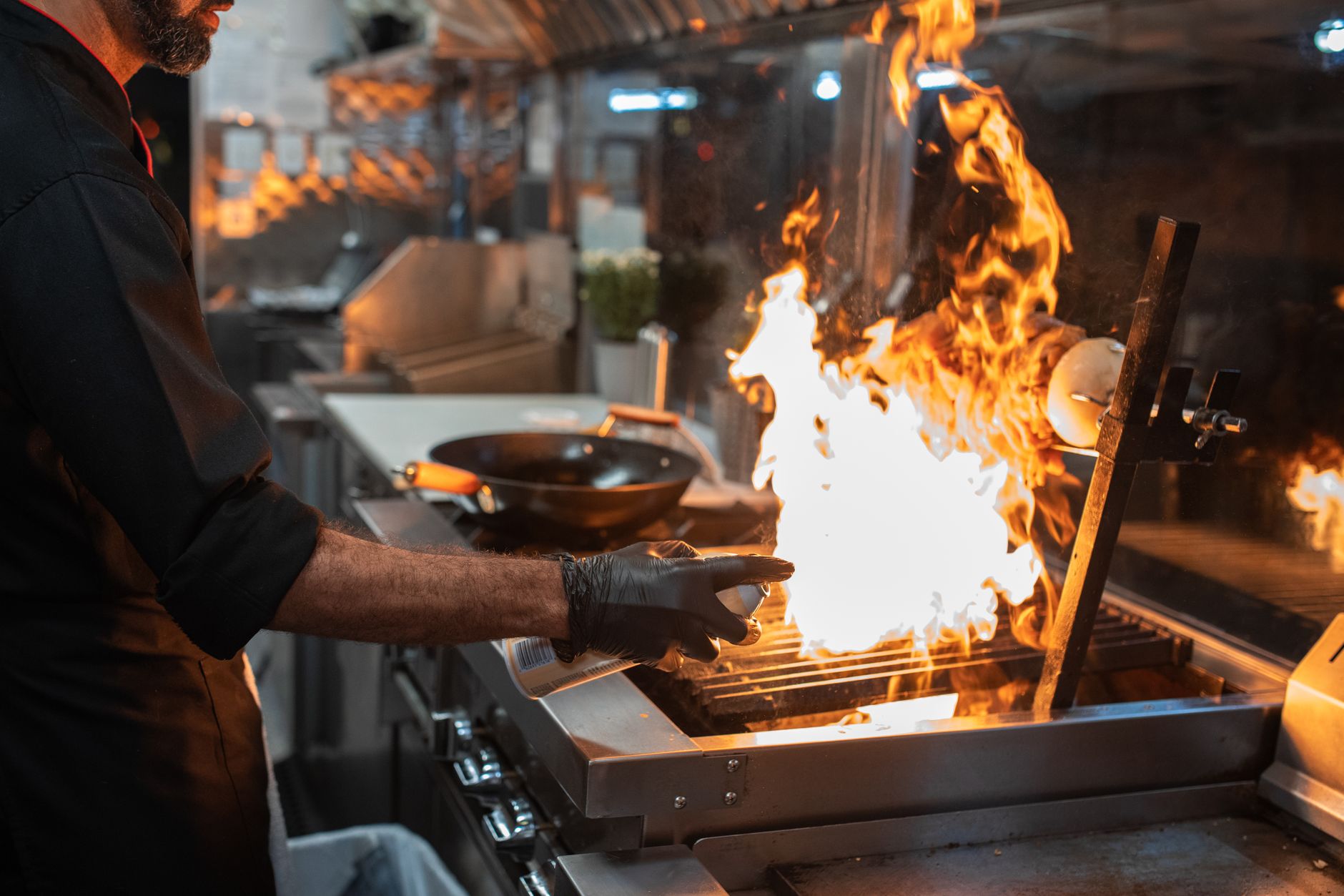 A chef cooking over a flaming grill