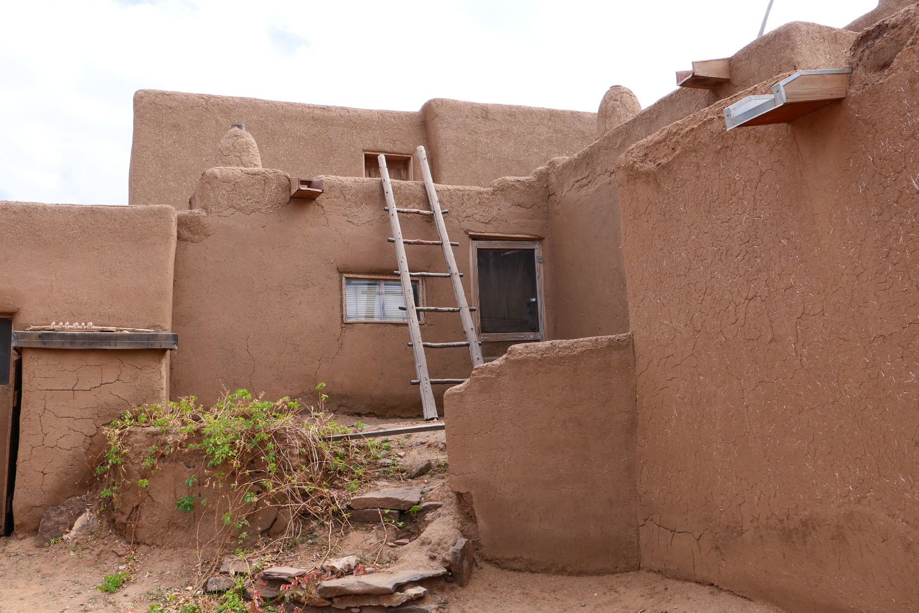 Best ladder stabilizer: a ladder leaning against an adobe wall