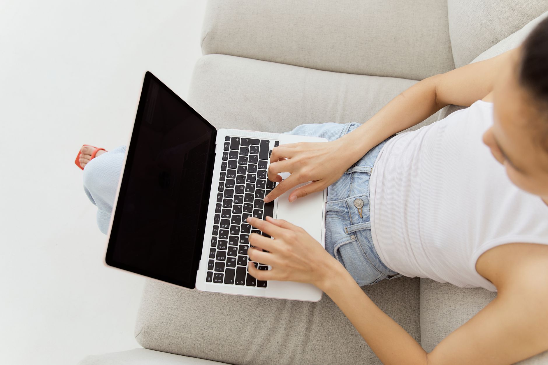 Hands typing on a laptop keyboard in a living room