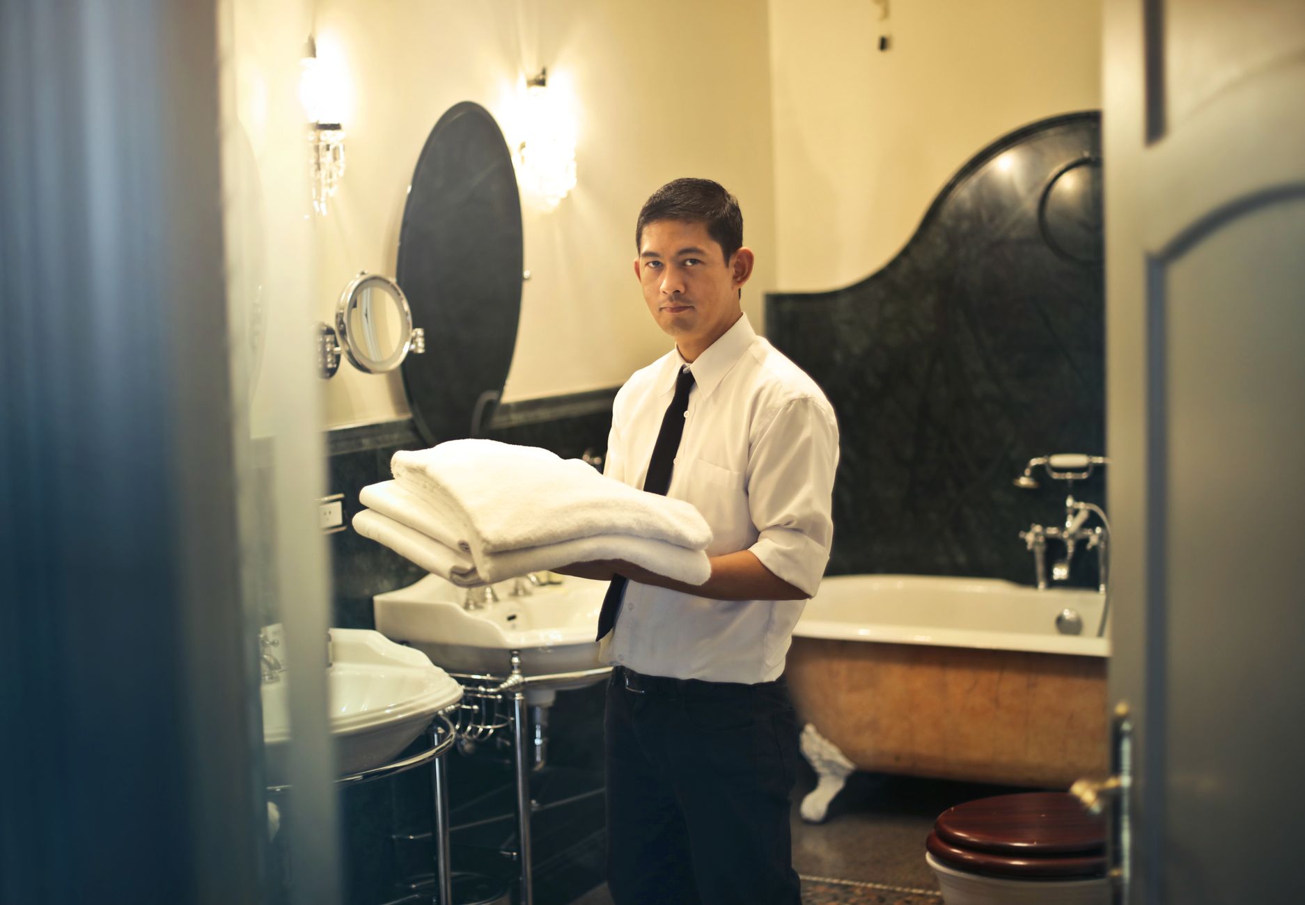 A man carrying folded towels in a bathroom