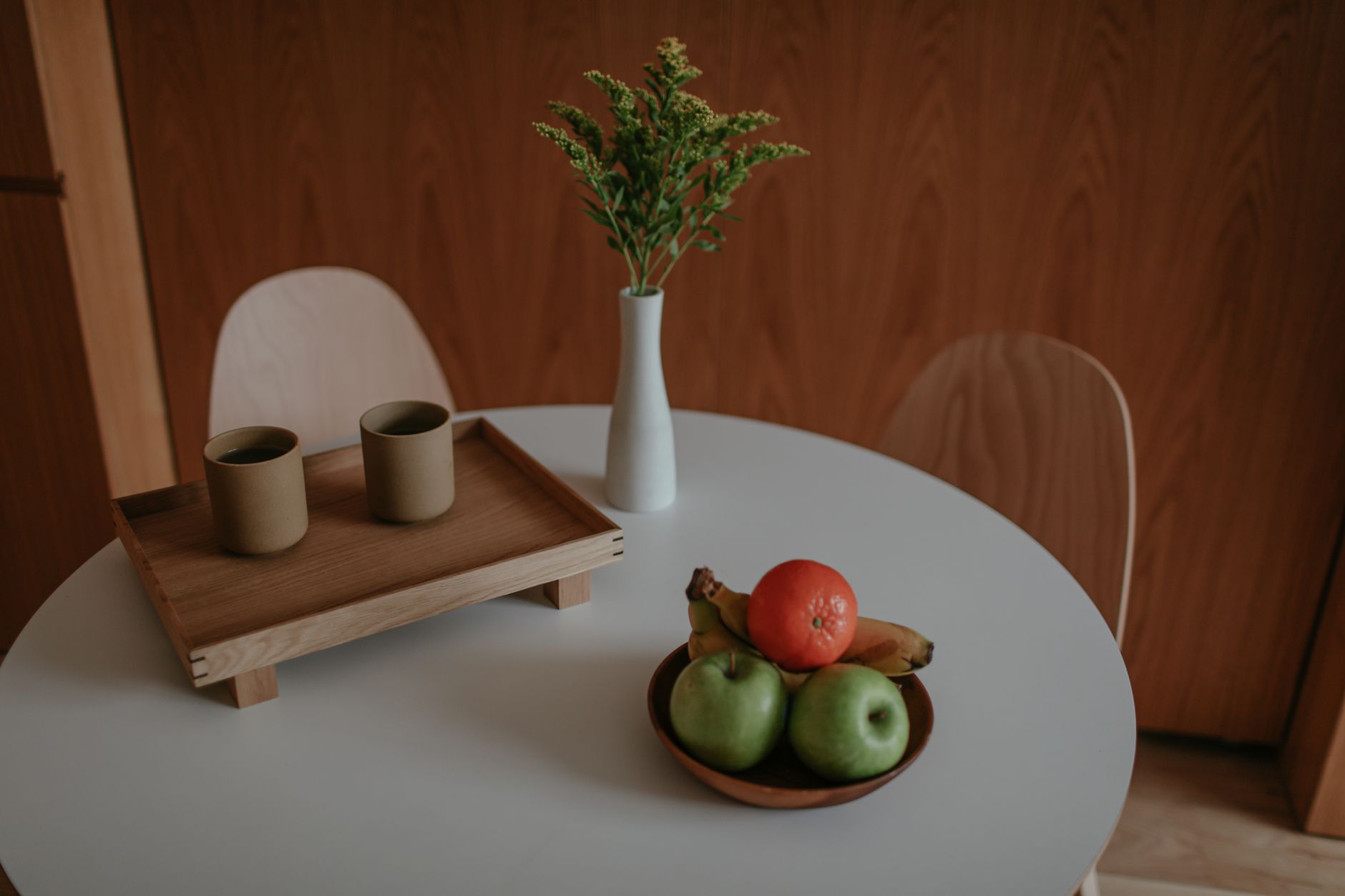 A wooden tray and fruit bowl on a dining table