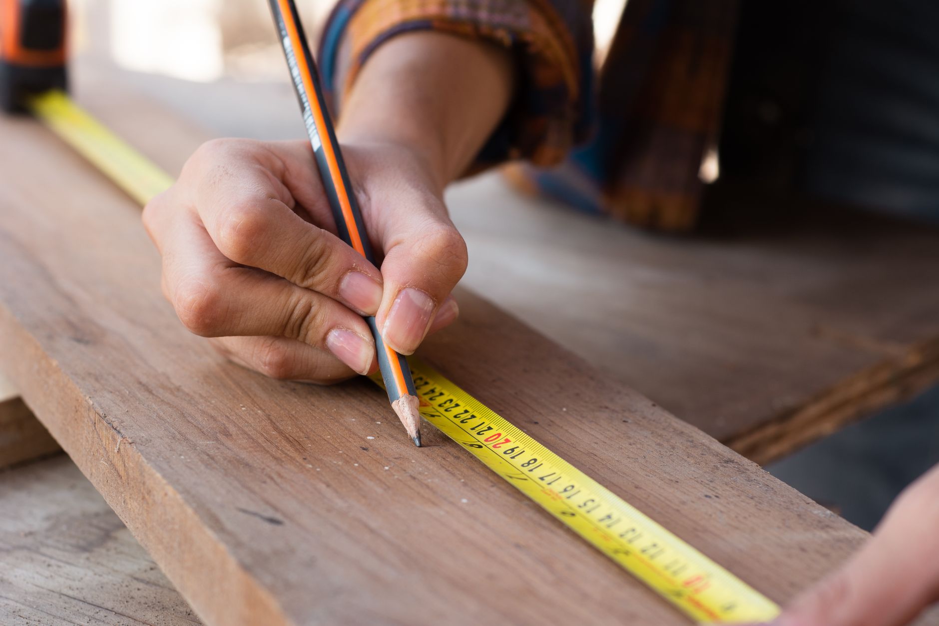 Hands measuring a wooden board before cutting