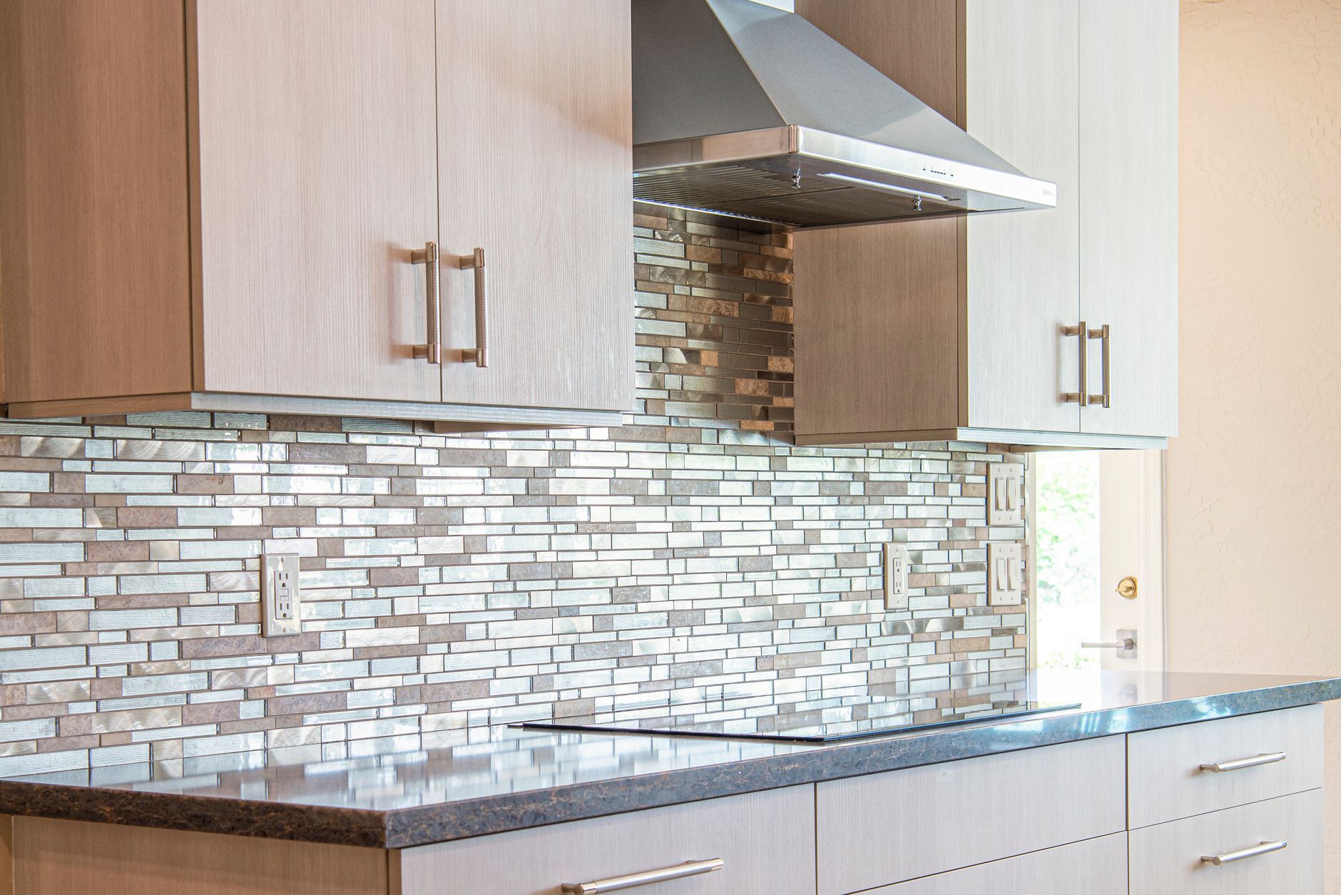 A tiled kitchen backsplash under wood cabinets